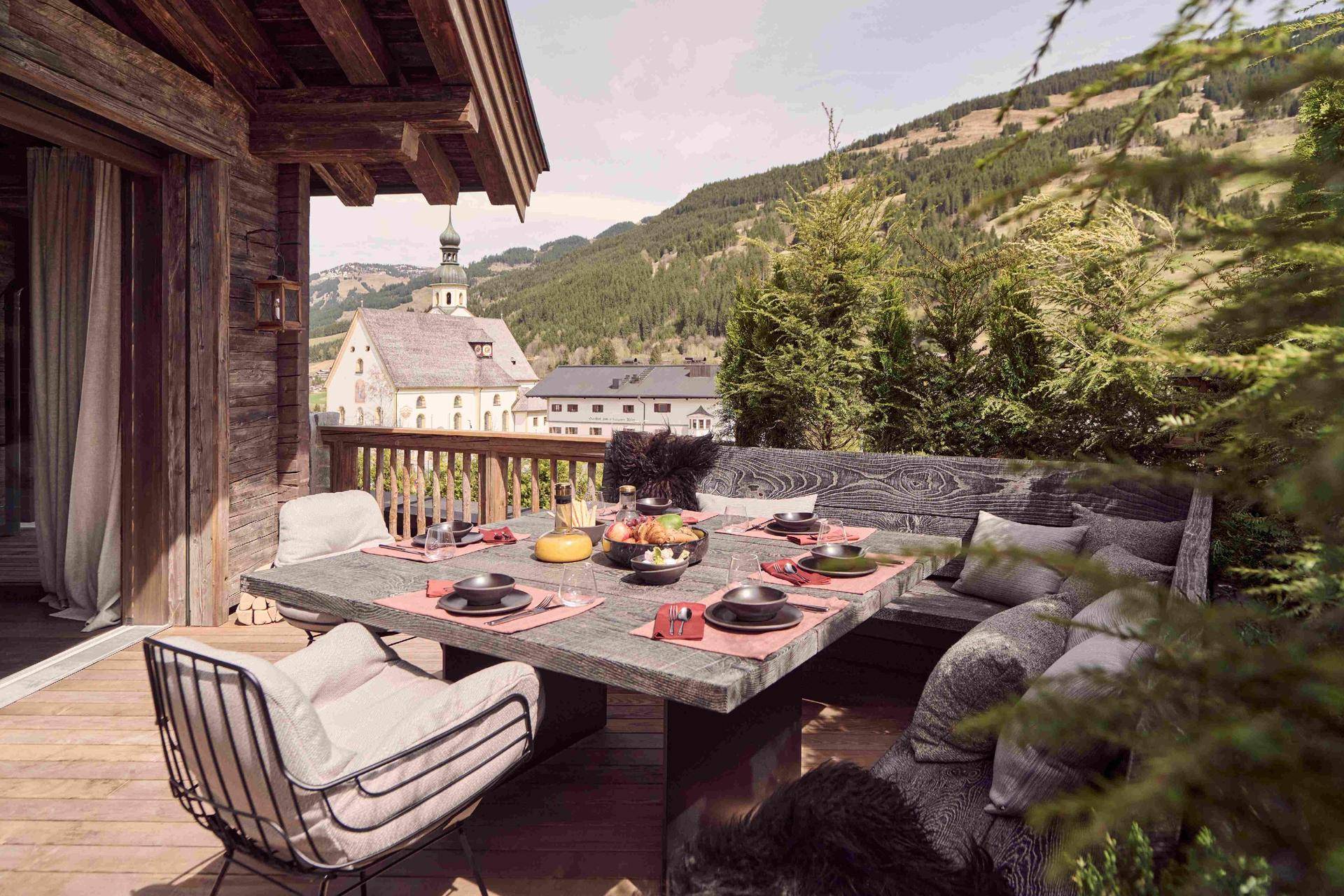Großzügige Terrasse mit Esstisch, Holzbänken und malerischem Blick auf die umliegenden Berge.