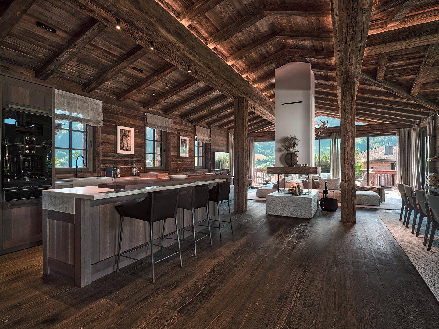 Moderne offene Küche mit Kochinsel und Barhockern, integriert in einen luxuriösen Wohnbereich im Chalet-Stil.