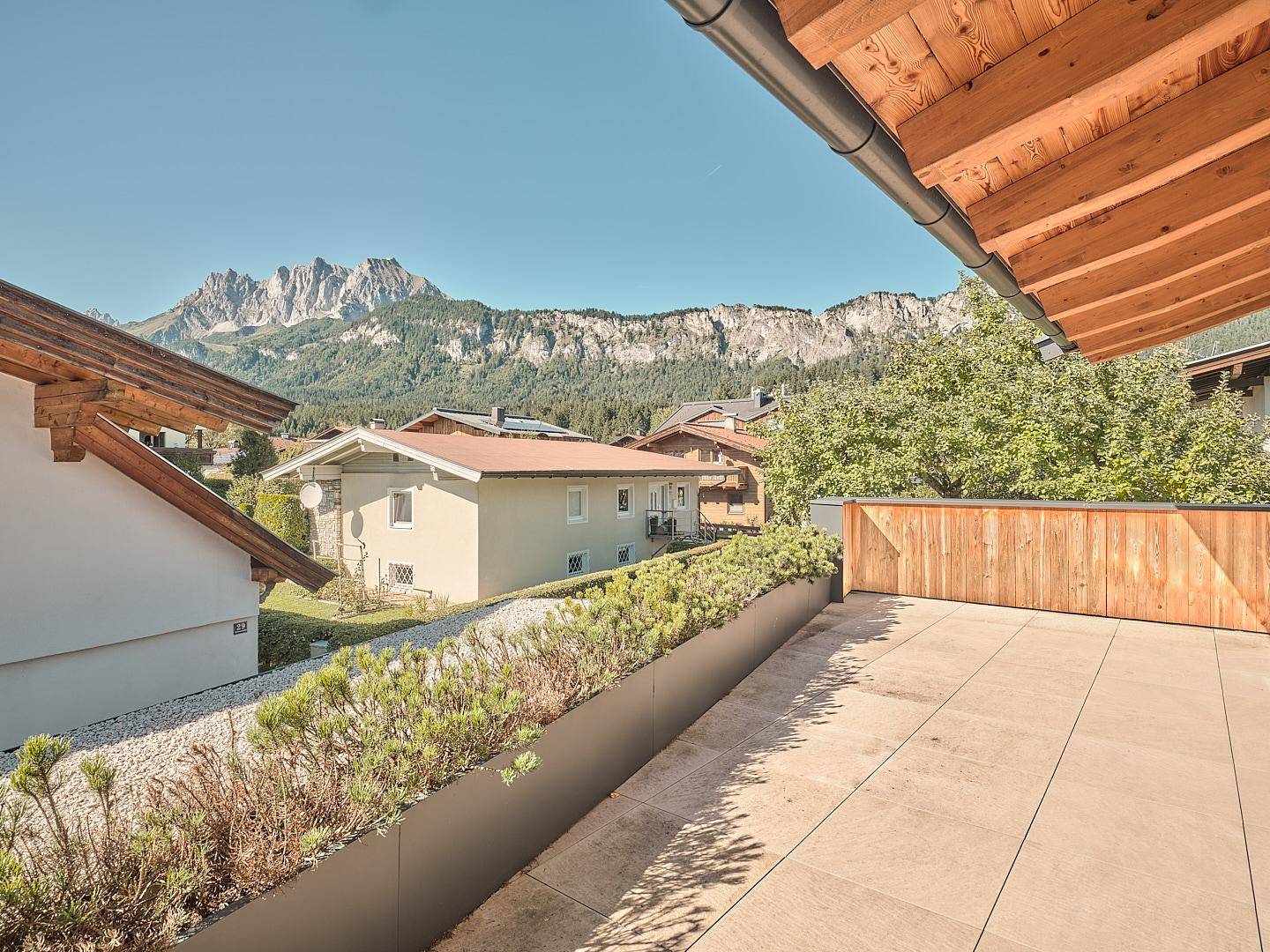 Geräumige Dachterrasse mit Panoramablick auf die umliegende Berglandschaft und Häuser.