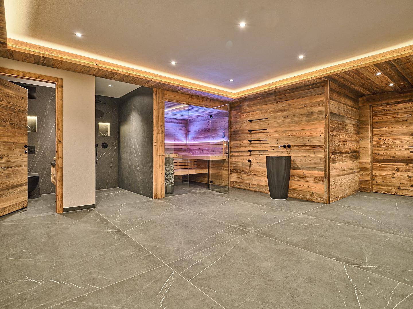 Exklusiver Wellnessbereich mit moderner Sauna, großformatigen Fliesen und Holzwänden.