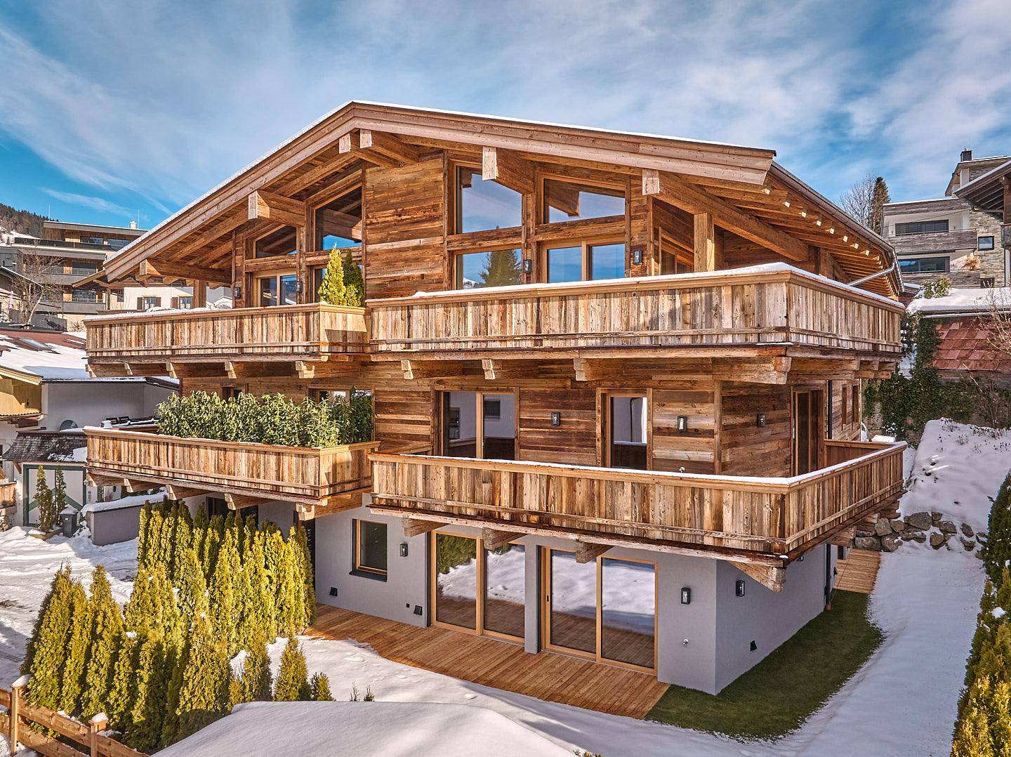 Luxuriöses Holzchalet mit mehreren Balkonen und traditioneller Architektur in verschneiter Berglandschaft.