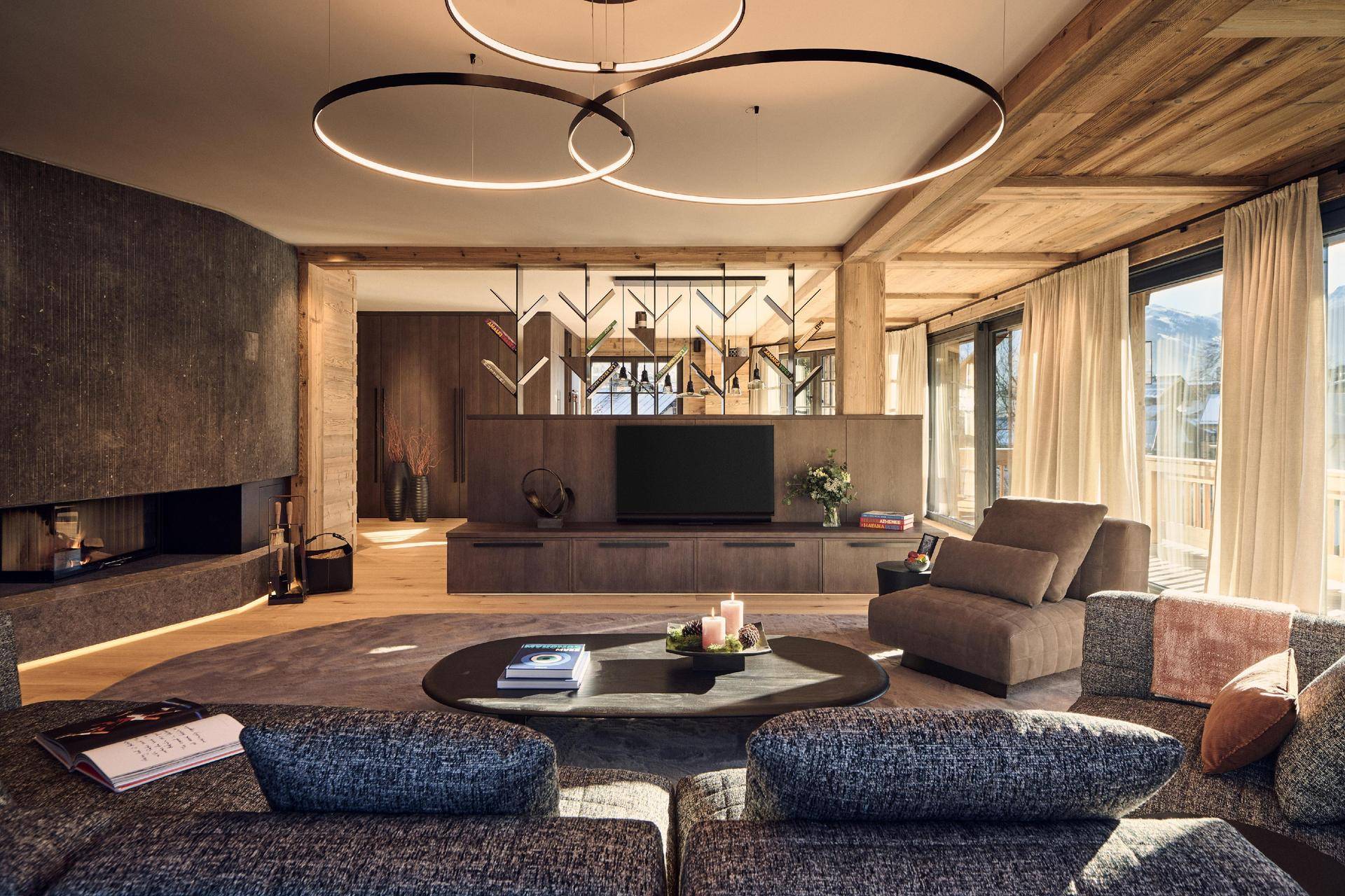 Geräumiges Wohnzimmer mit modernem Kamin, bequemen Sofas und Holzakzenten in alpiner Atmosphäre.