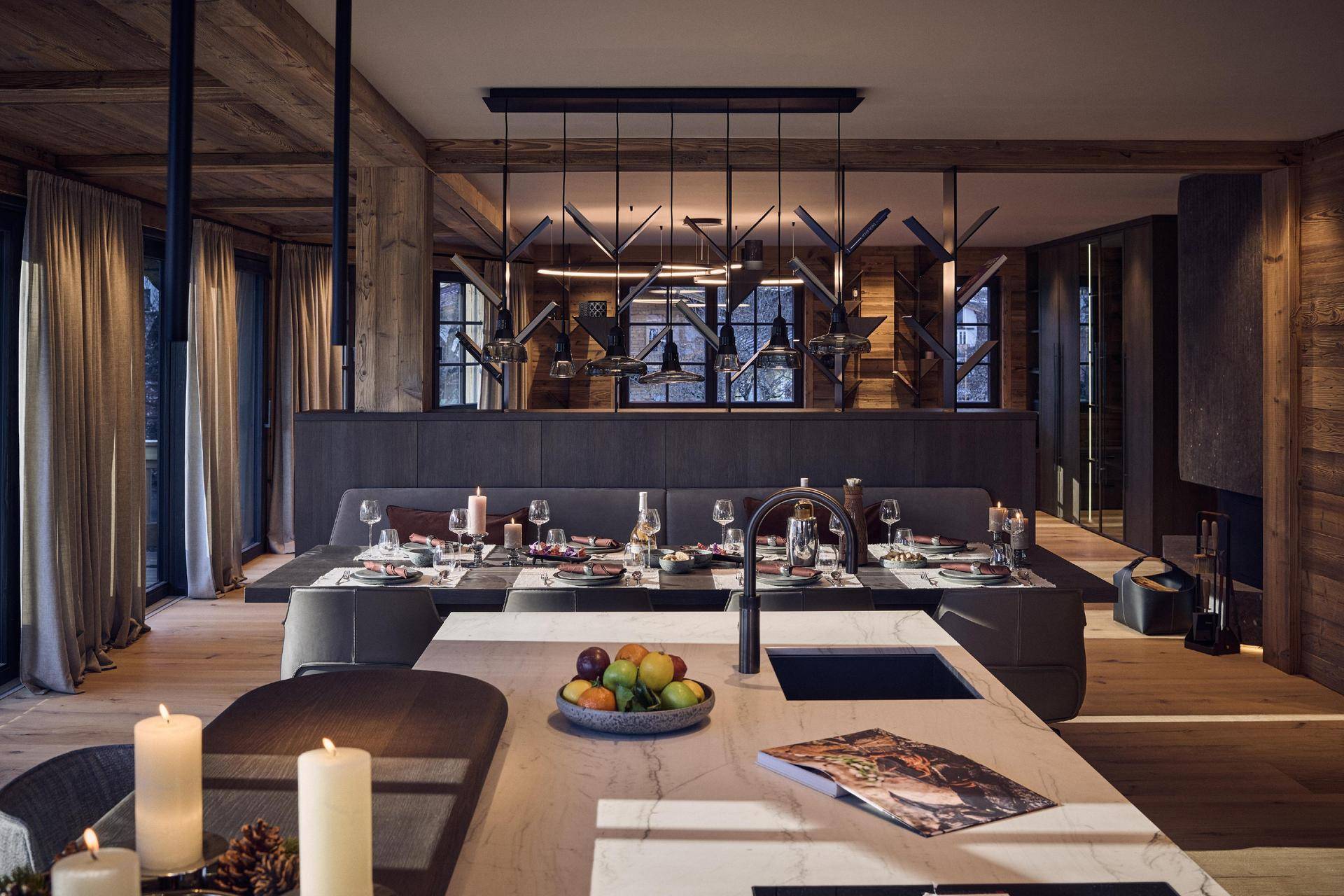 Eleganter Essbereich mit langer Tafel, modernen Pendelleuchten und Holzakzenten im alpinen Stil.