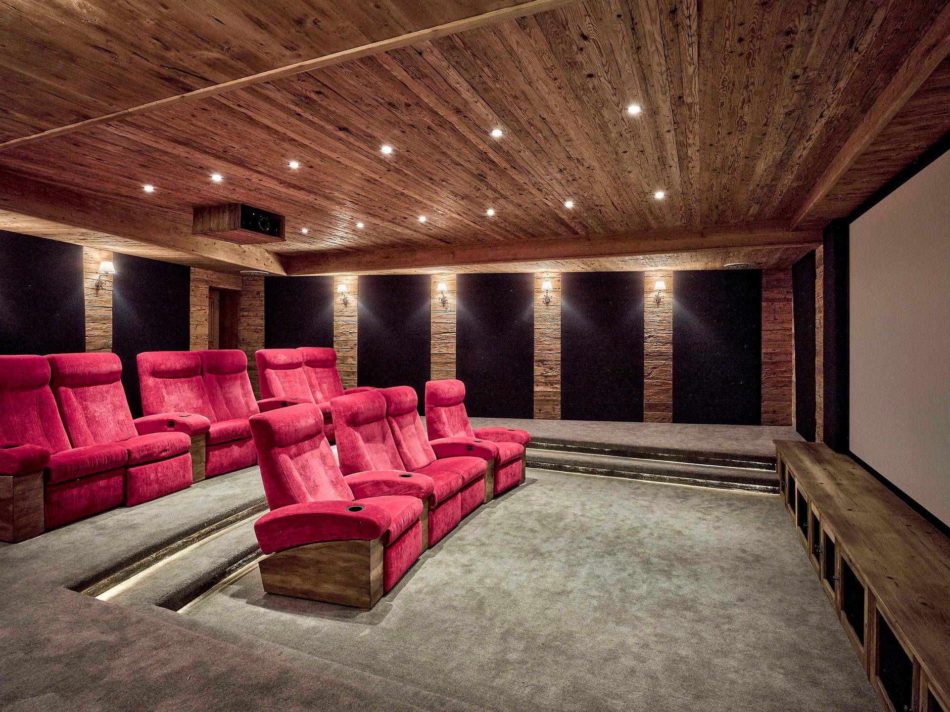 Privates Heimkino mit bequemen roten Sesseln und Holzvertäfelung für Filmerlebnisse.