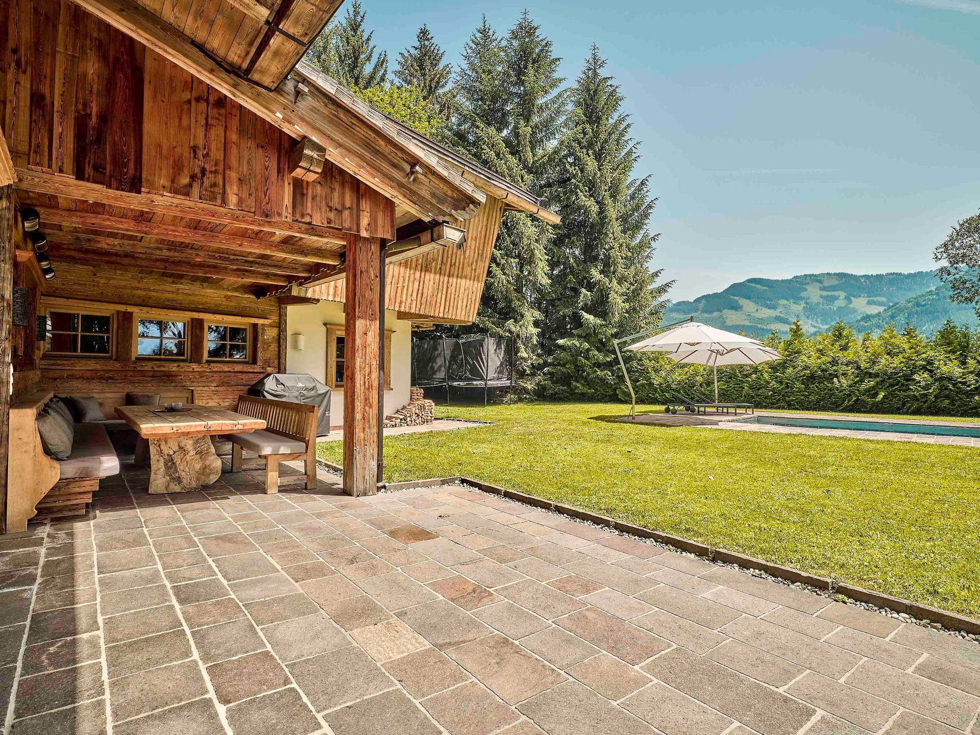 Überdachte Terrasse mit Esstisch und Bergblick, ideal für Mahlzeiten im Freien.
