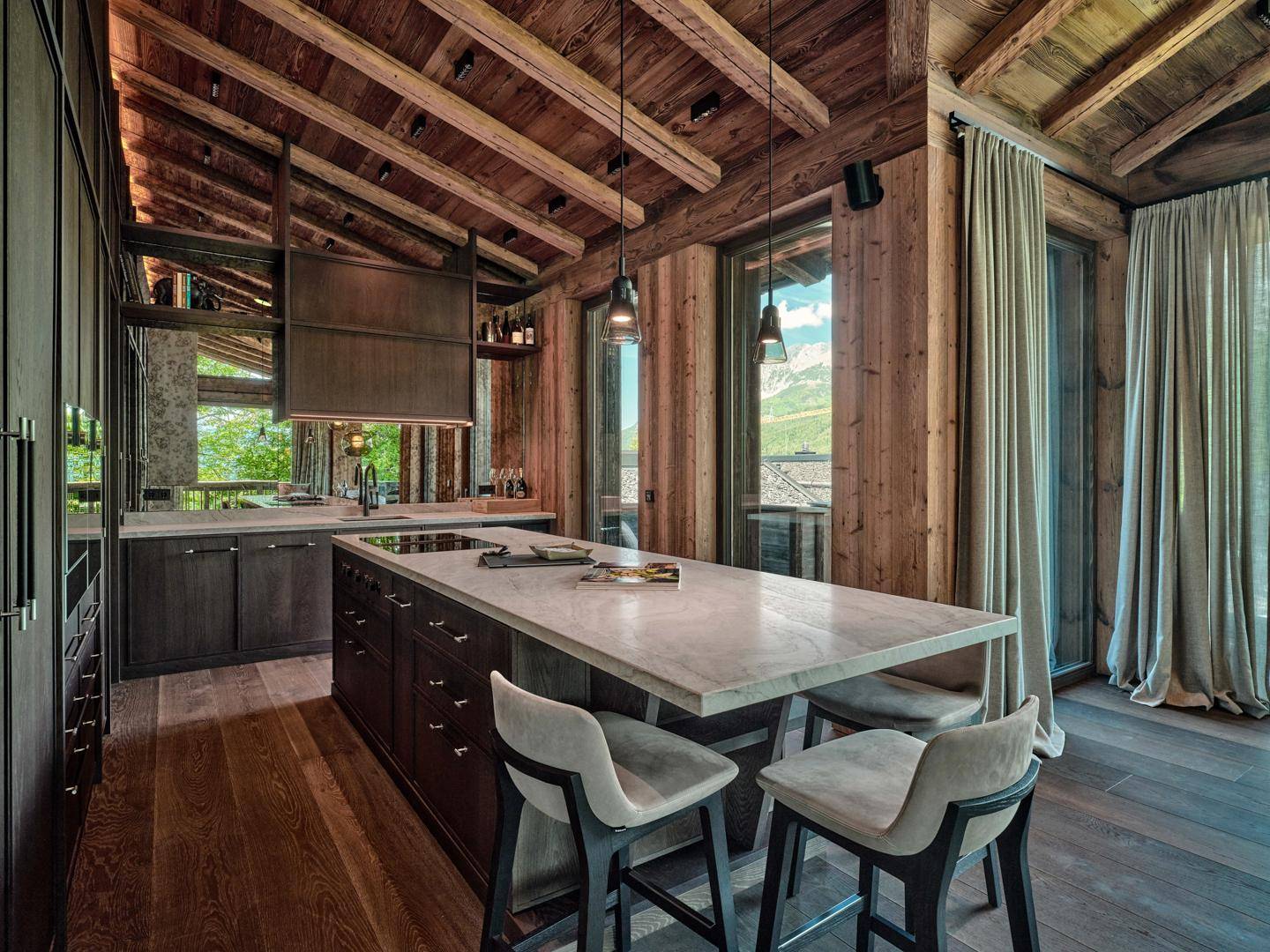 Moderne Küche im Chalet-Stil mit Holzbalkendecke, Kücheninsel und hochwertigen Geräten.