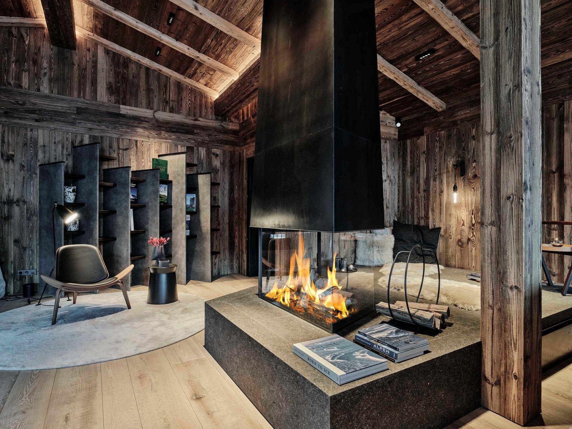 Gemütliches Wohnzimmer im Chalet-Stil mit modernem Kamin als Mittelpunkt und Holzbalkendecke.