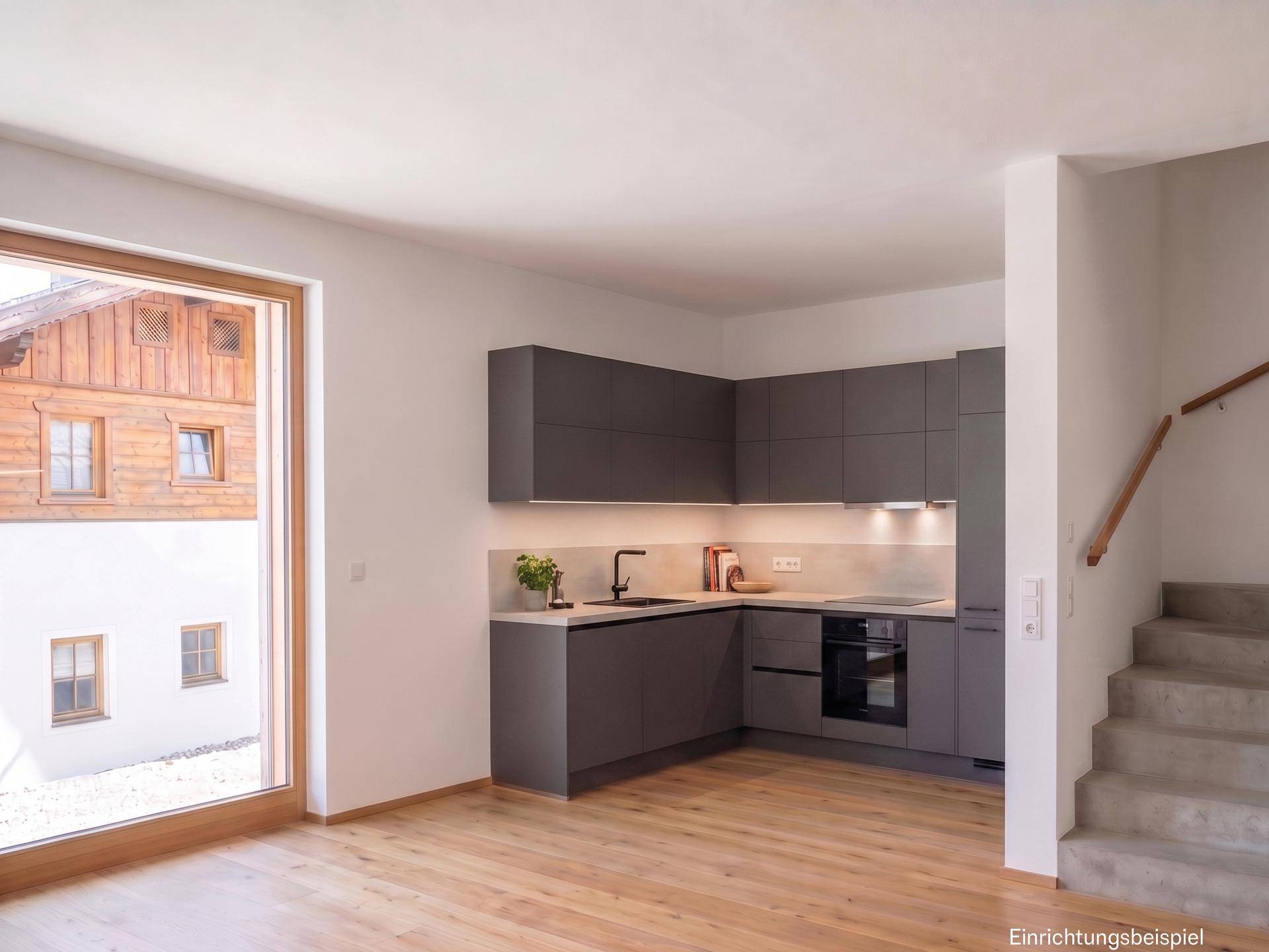 Moderne Einbauküche in Grau mit großem Fenster und Zugang zum Treppenhaus.