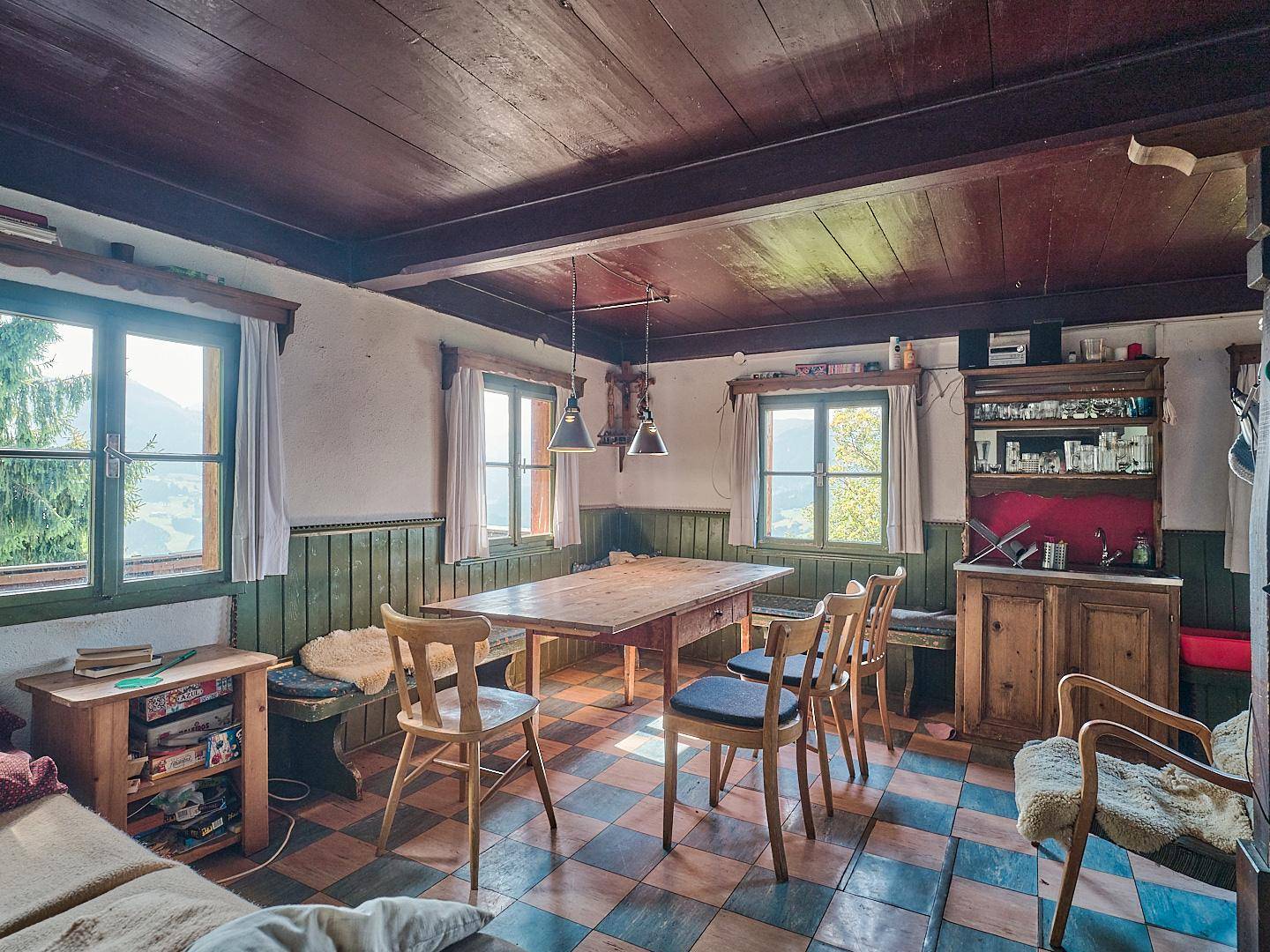 Rustikaler Essbereich mit Holztisch, Stühlen und kariertem Fliesenboden, umgeben von Holzvertäfelung.
