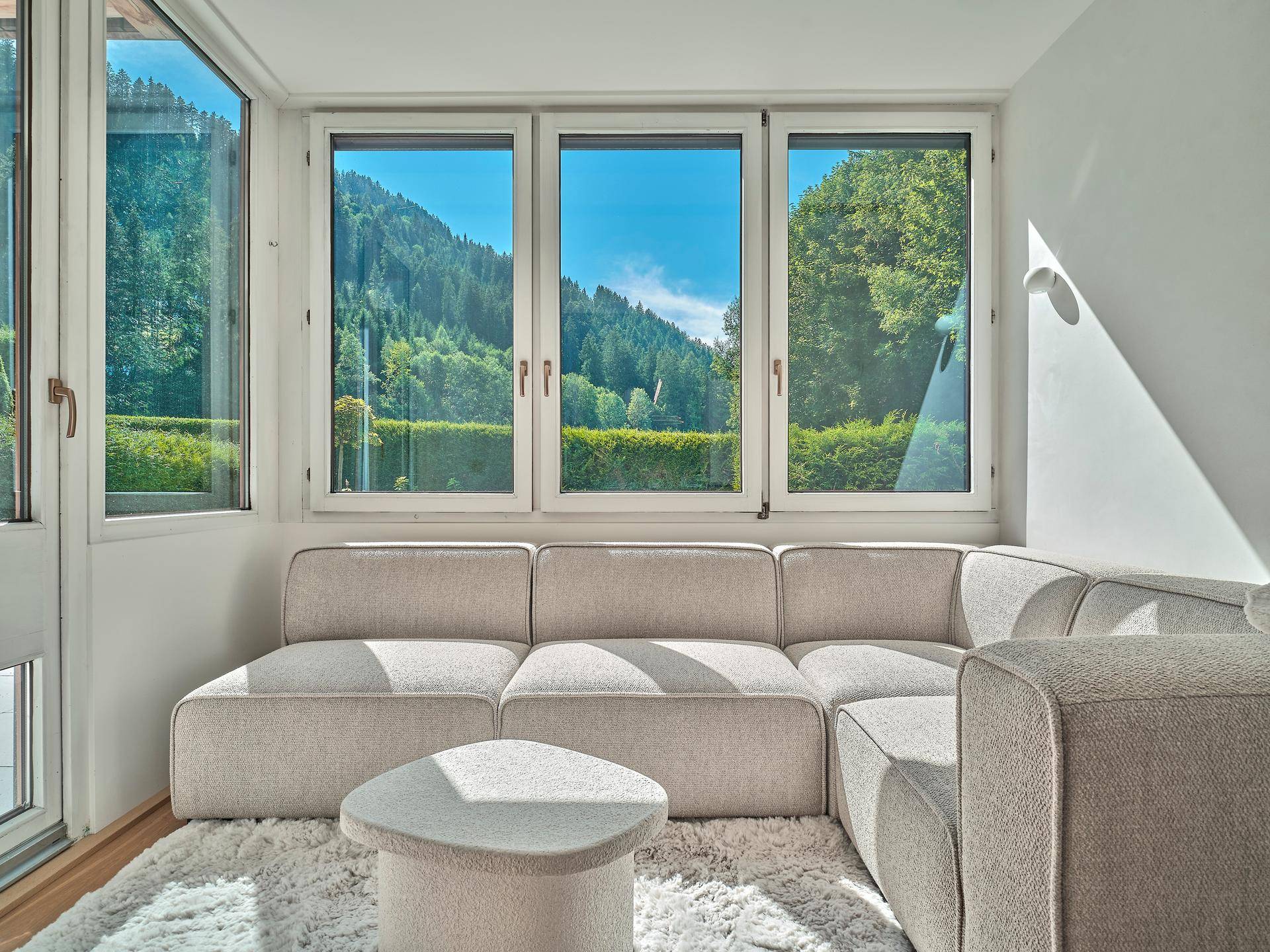 Gemütlicher Sitzbereich mit großzügigen Fenstern und beeindruckendem Blick auf Berge und Natur.