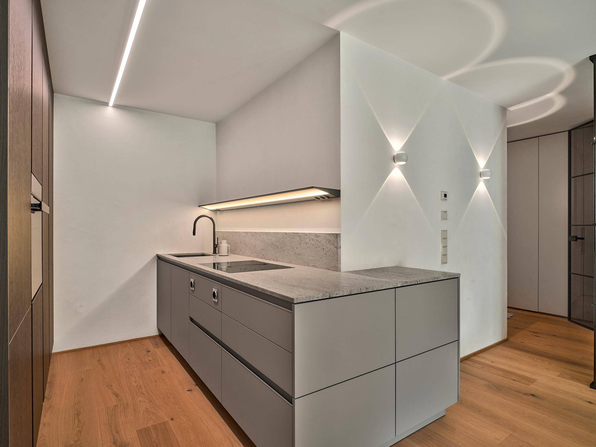 Moderne Küche mit grauen Unterschränken, Granitarbeitsplatte und integrierten Geräten.