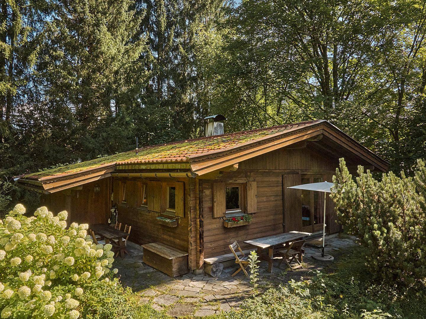 Rustikales Holzchalet mit einer einladenden Steinterrasse und Gartenmöbeln im Grünen.