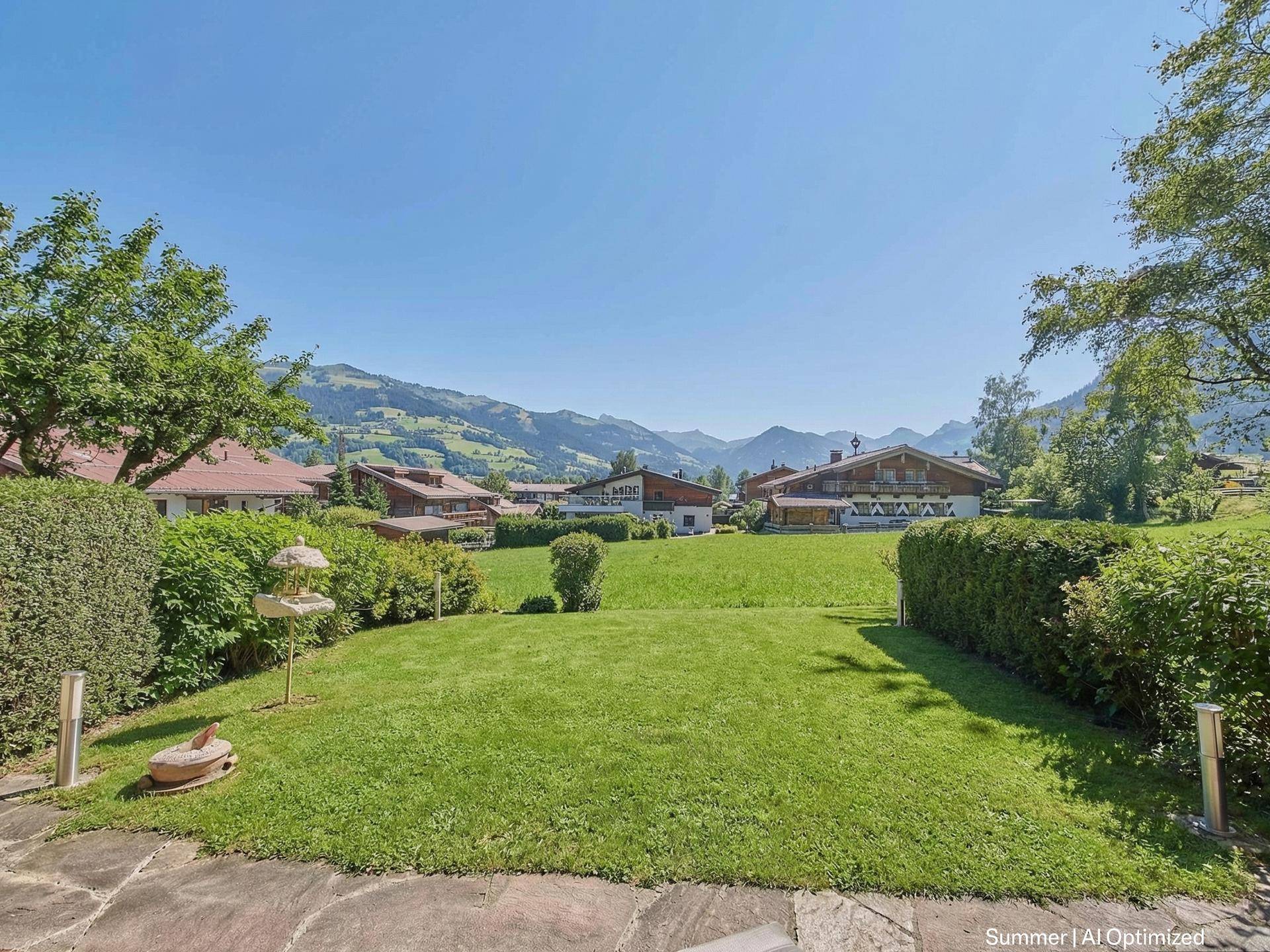 Gepflegter Garten mit Rasenfläche, Hecken und malerischem Blick auf die umliegende Berglandschaft.