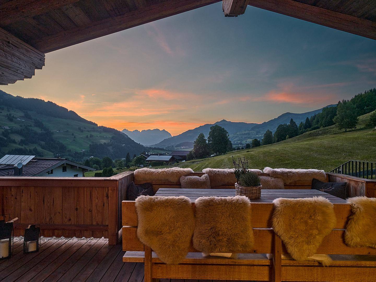 Überdachte Holzterrasse mit Sitzgelegenheiten und weitem Blick auf die Berglandschaft.