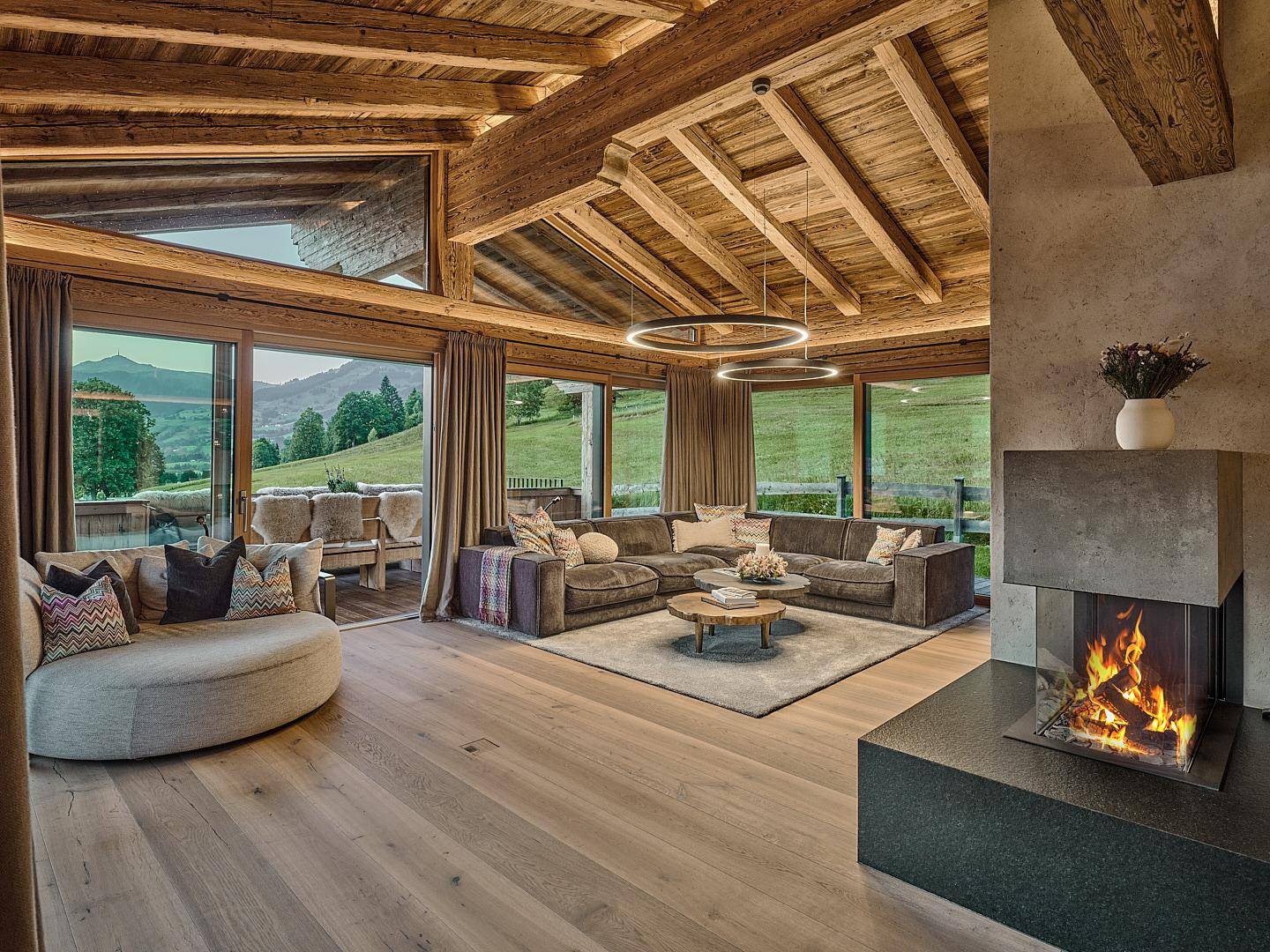 Gemütliches Wohnzimmer im Chalet-Stil mit Holzbalken, Kamin und Bergblick.