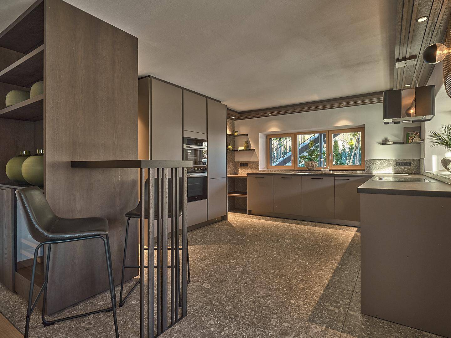 Moderne Küche mit integrierten Geräten, Frühstücksbar und stilvollem Steinboden.