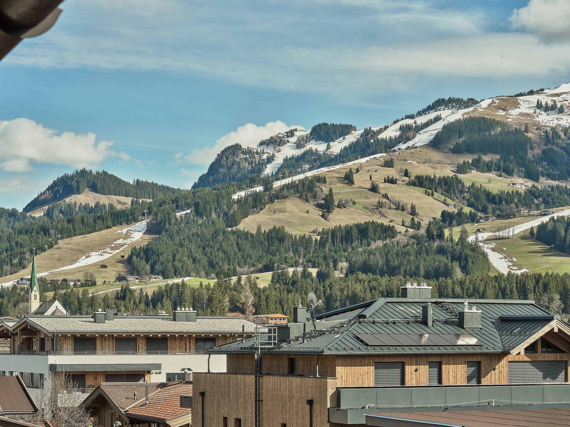 Panoramablick auf schneebedeckte Berge und traditionelle Gebäude in einer malerischen alpinen Landschaft.