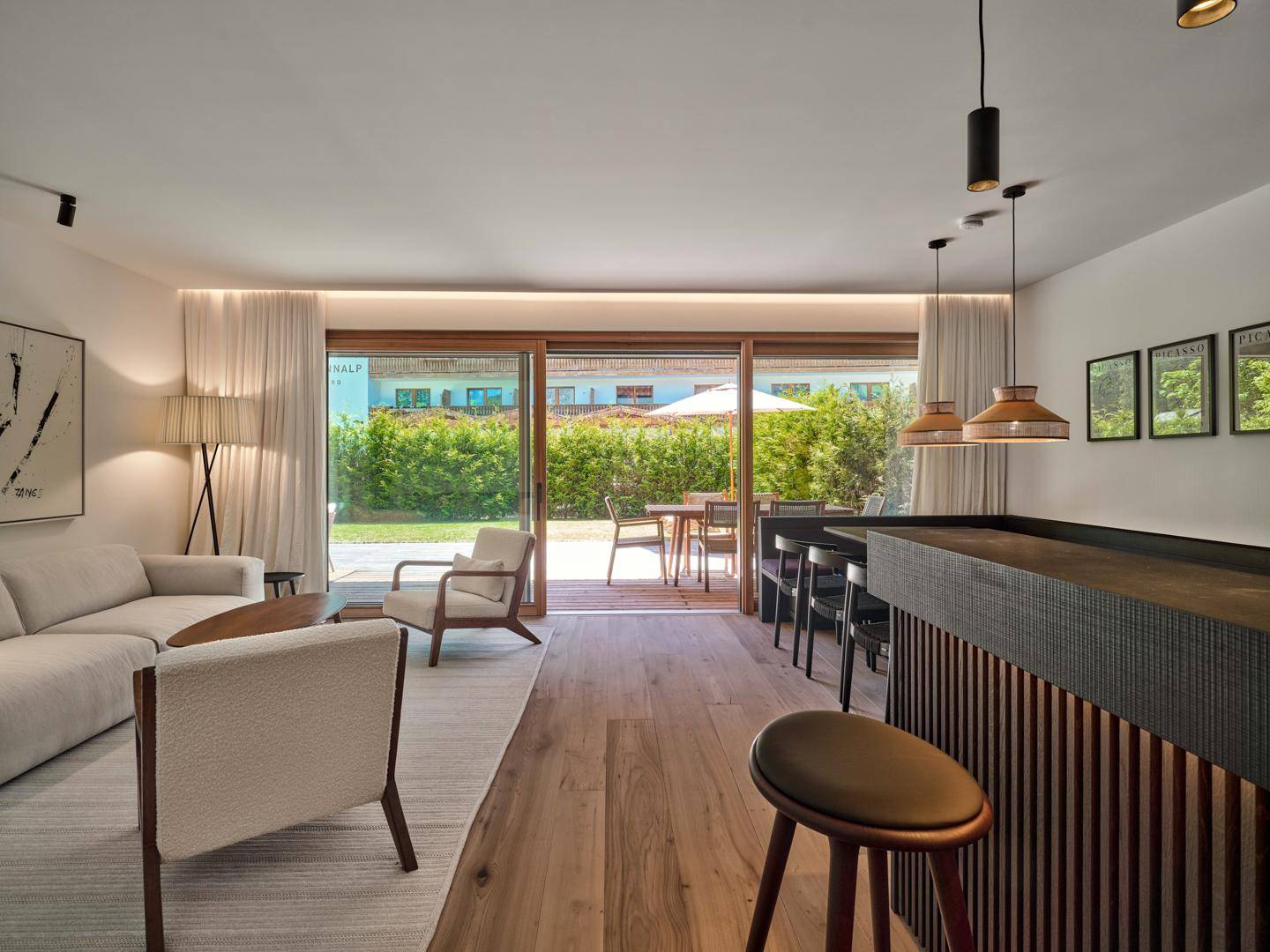 Heller Wohnbereich mit Holzboden, bequemen Möbeln und direktem Zugang zur grünen Terrasse.