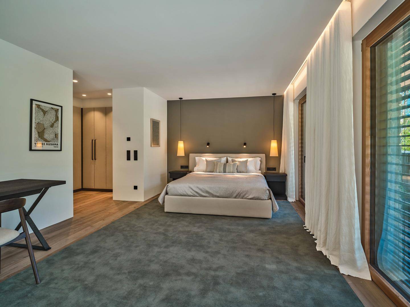 Modernes Schlafzimmer mit großem Bett, Einbauschränken und viel Tageslicht durch die Fenster.