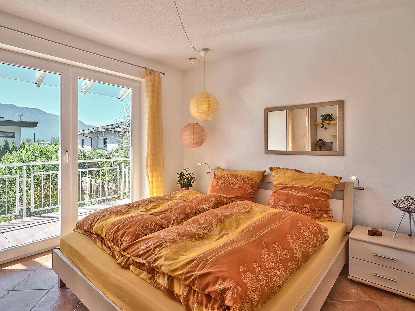 Schlafzimmer mit Balkonzugang, hellem Interieur und malerischem Bergblick.