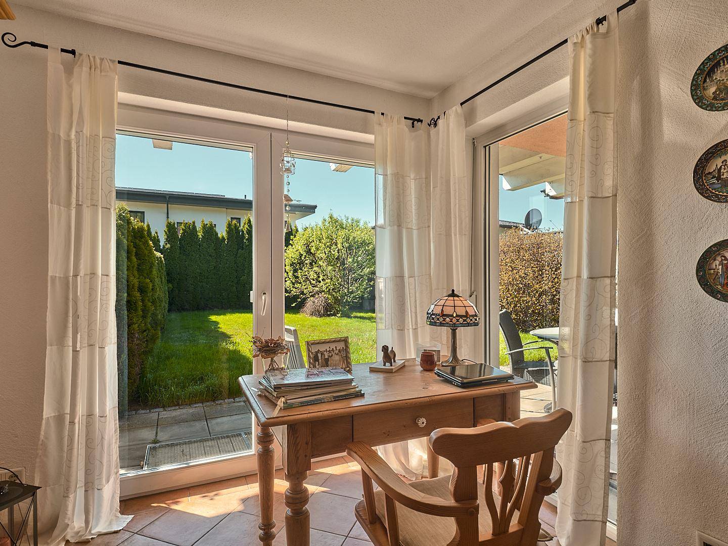 Heller Arbeitsplatz mit Schreibtisch am Fenster und direktem Blick in den grünen Garten.