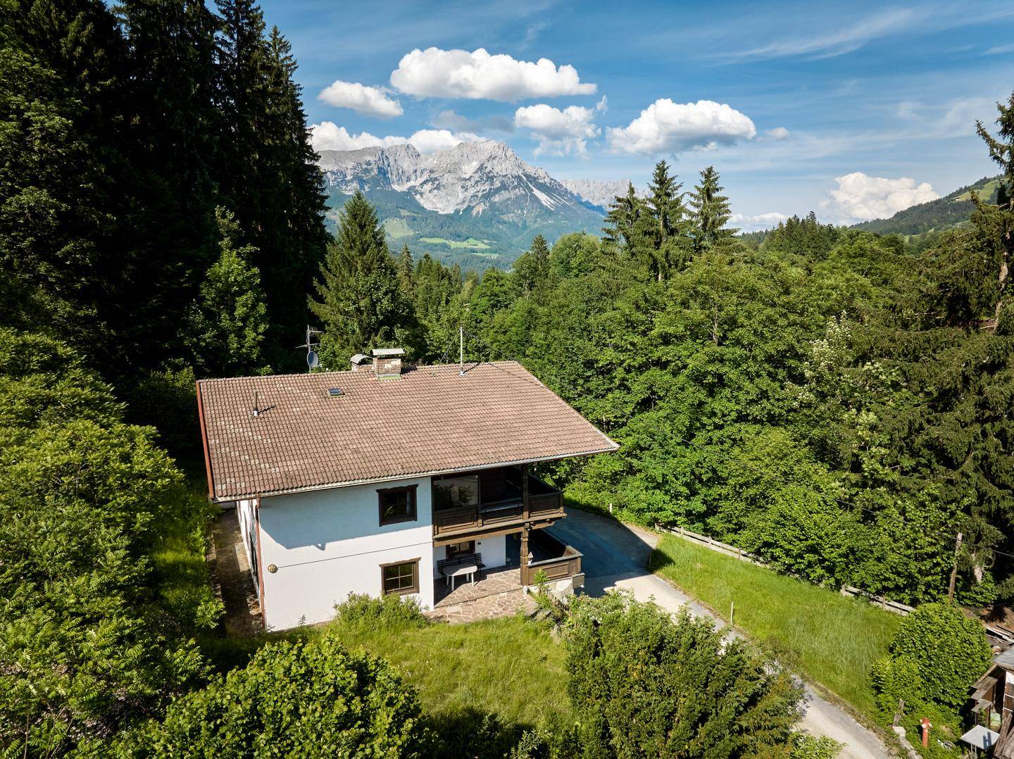 Charmantes Haus in alpiner Landschaft mit Bergblick und umgeben von dichtem Wald.