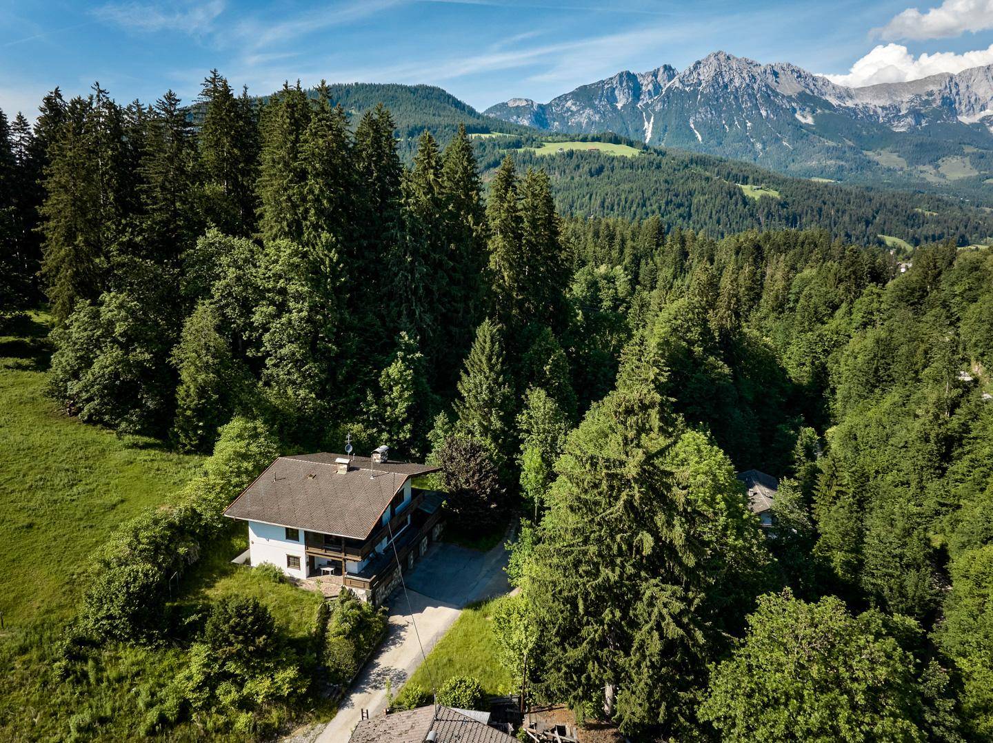 Panoramablick auf das Haus in einer malerischen Berglandschaft mit weiten Wäldern und Wiesen.