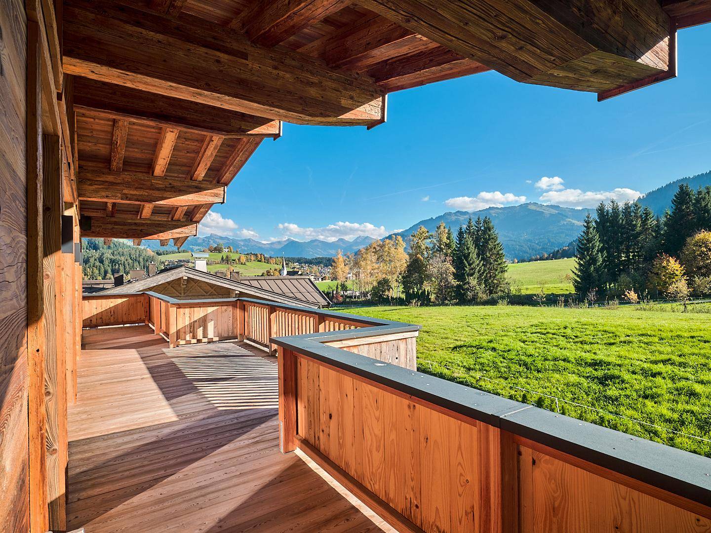 Geräumiger Holzbalkon mit atemberaubendem Blick auf die Berge und grüne Landschaft.