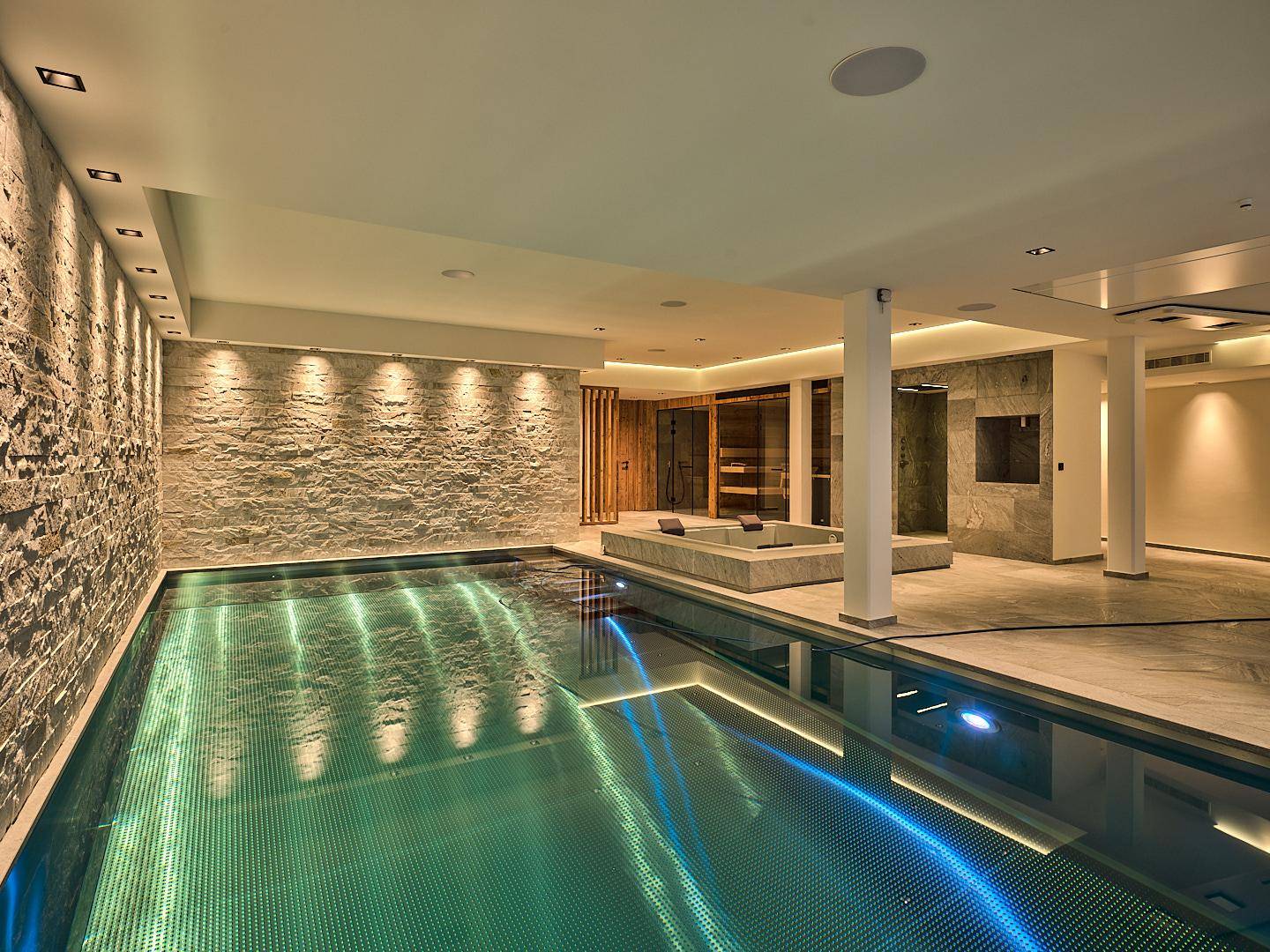 Exklusiver Wellnessbereich mit Innenpool, Steinwand und Sauna für pure Entspannung.
