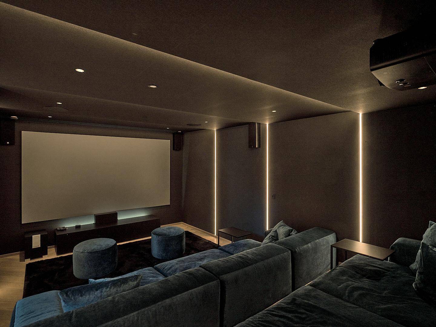 Exklusiver Heimkinoraum mit großer Leinwand, bequemen Sofas und stimmungsvoller Beleuchtung.