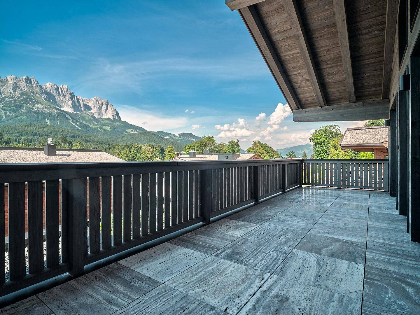 Geräumiger Balkon mit Steinboden und weitem Blick auf die umliegende Berglandschaft.