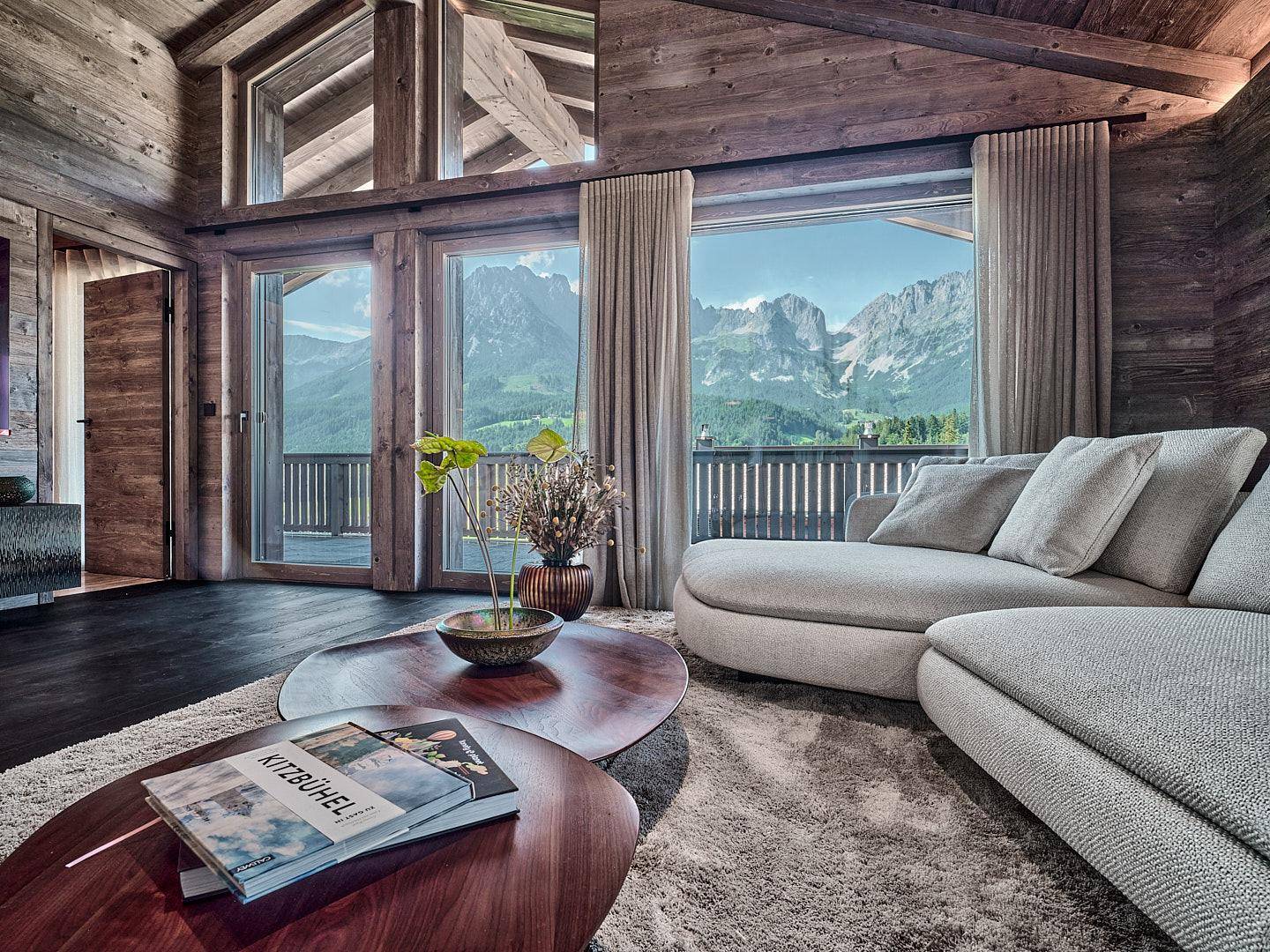 Gemütliches Wohnzimmer im Chalet-Stil mit Holzwänden, großen Fenstern und atemberaubendem Bergblick.