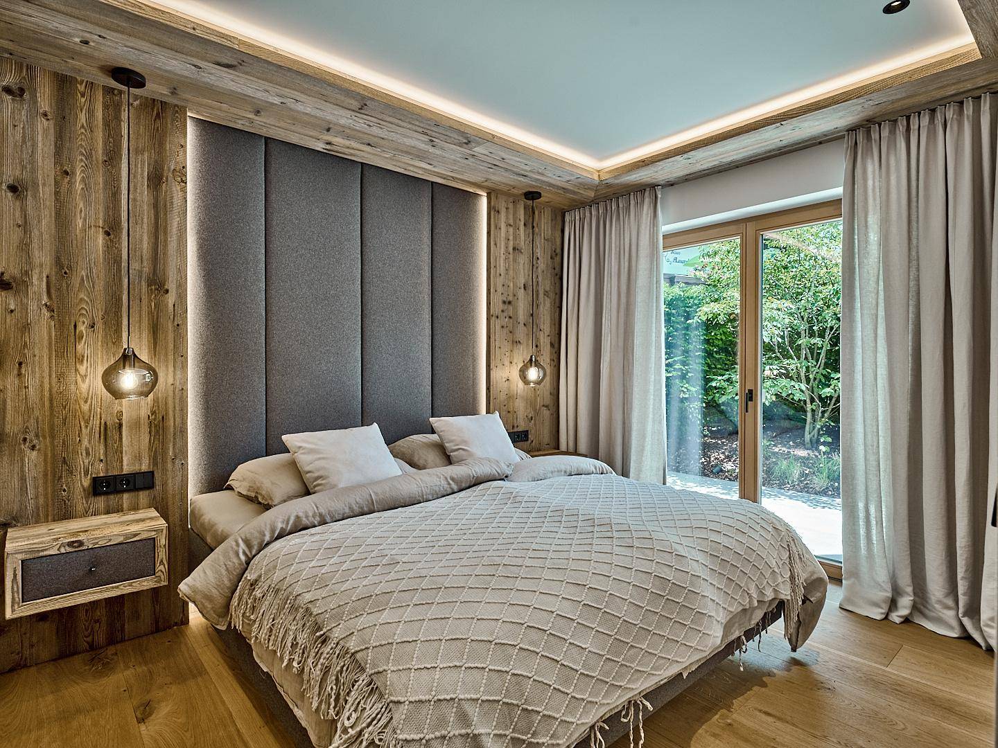 Gemütliches Schlafzimmer mit Holzwänden, großem Bett und direktem Zugang zu einem Außenbereich.