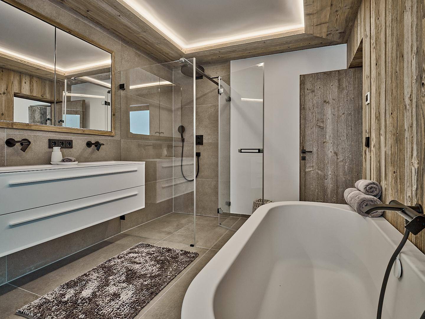 Modernes Badezimmer mit begehbarer Dusche, Badewanne und Doppelwaschbecken in Holzoptik.
