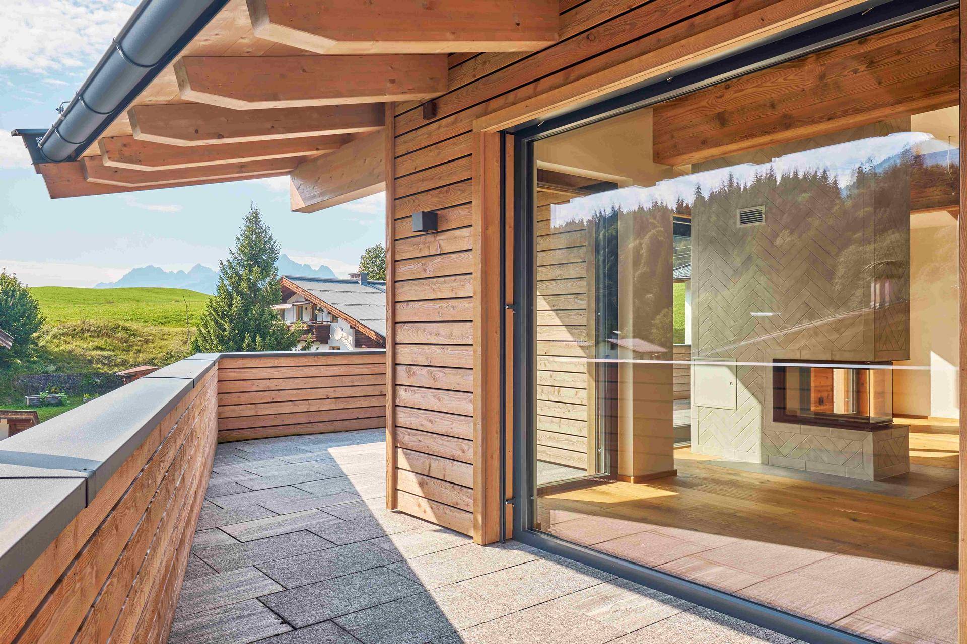 Großer Balkon mit Steinboden und Panoramablick auf die Berge, direkt zugänglich vom Wohnbereich.