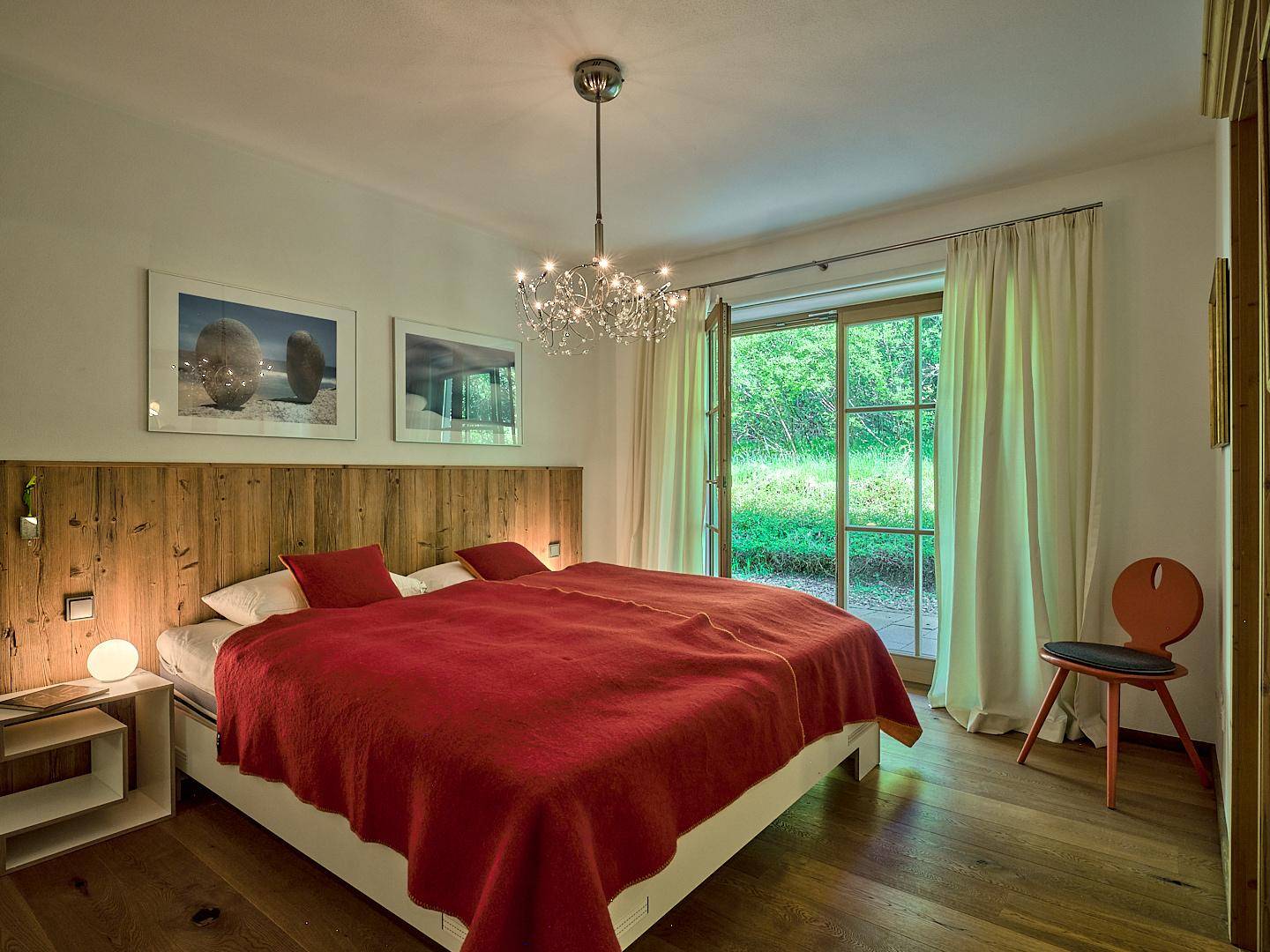 Gemütliches Schlafzimmer mit Holzboden, großem Bett und direktem Zugang zum Gartenbereich.