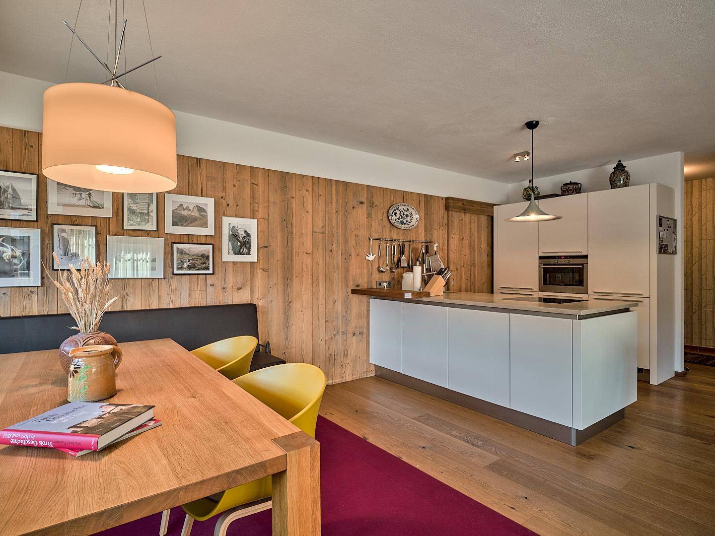 Moderner Essbereich mit Holztisch und offener Küche mit Kücheninsel und Einbaugeräten.