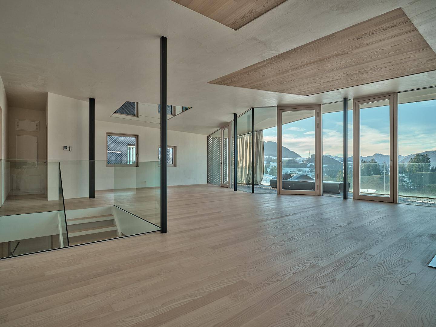 Geräumiger Wohnbereich mit Eichenparkett, offener Treppe und weitem Blick auf die umliegende Natur.