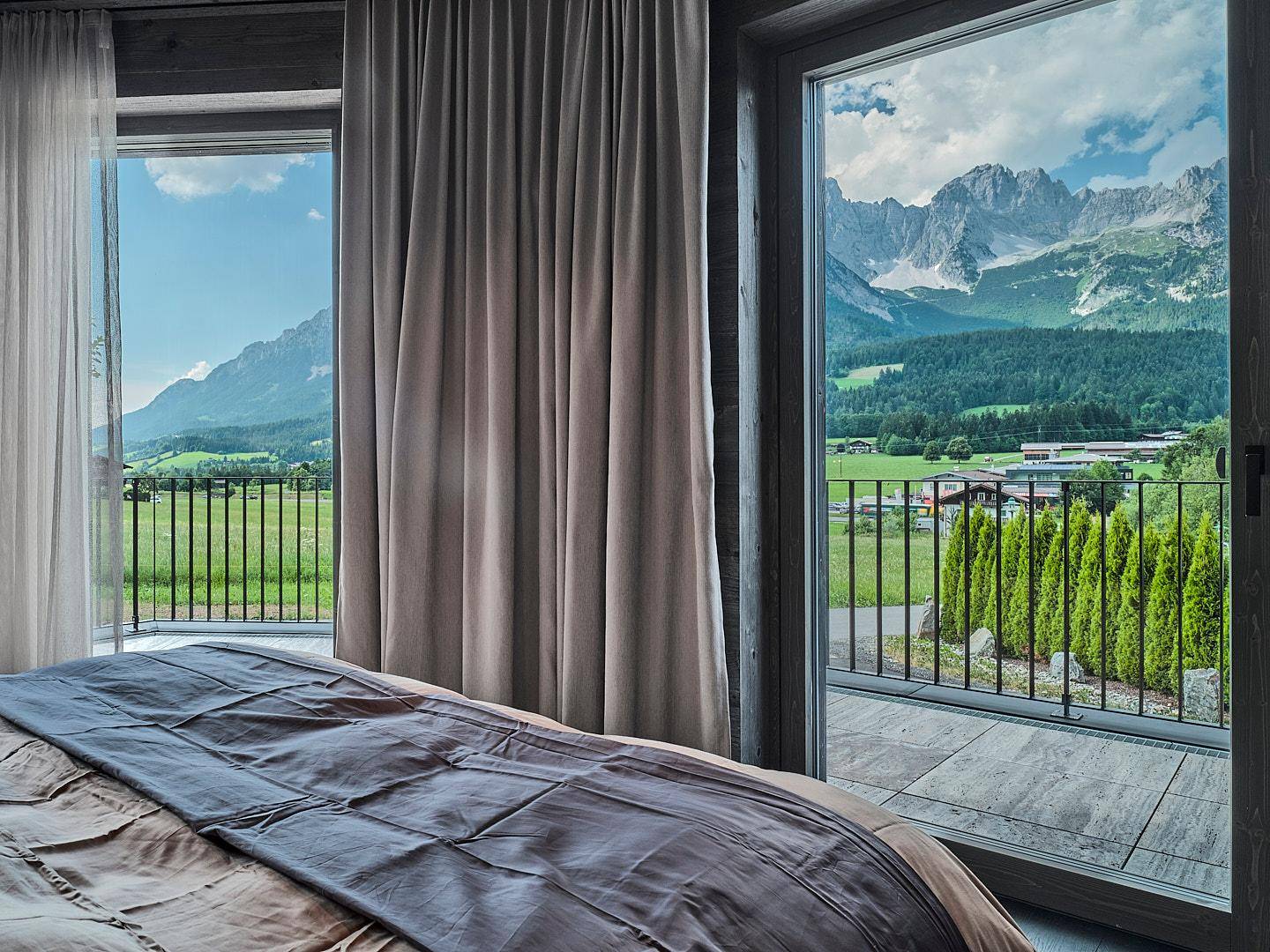 Gemütliches Schlafzimmer mit großen Fenstern und atemberaubendem Blick auf die schneebedeckten Berge.
