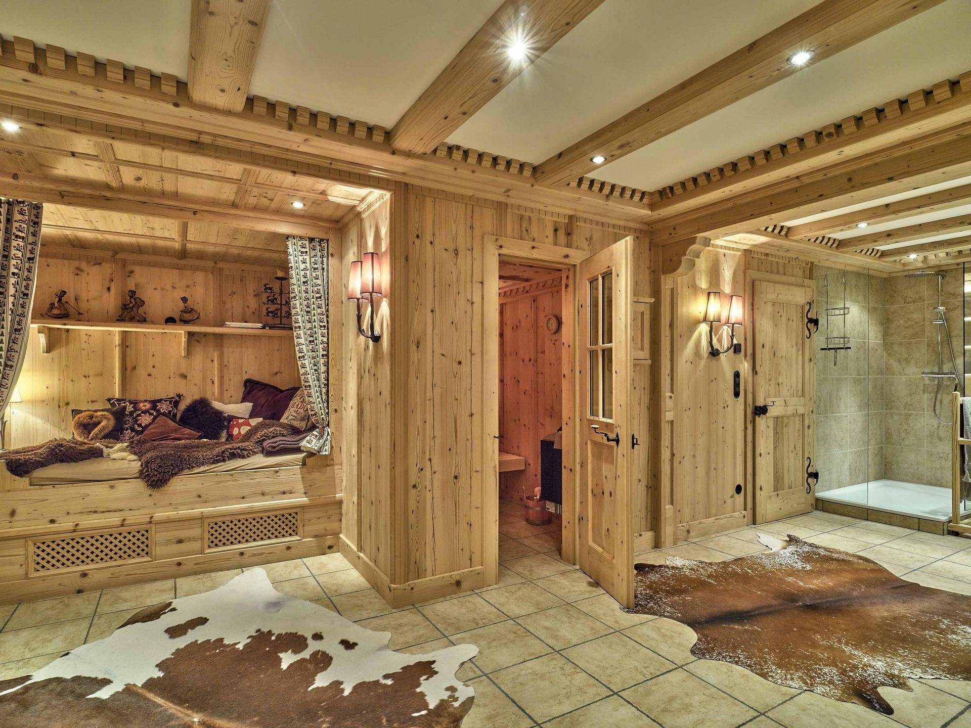 Exklusiver Wellnessbereich mit Sauna, Ruheliege und begehbarer Dusche in Holzausstattung.