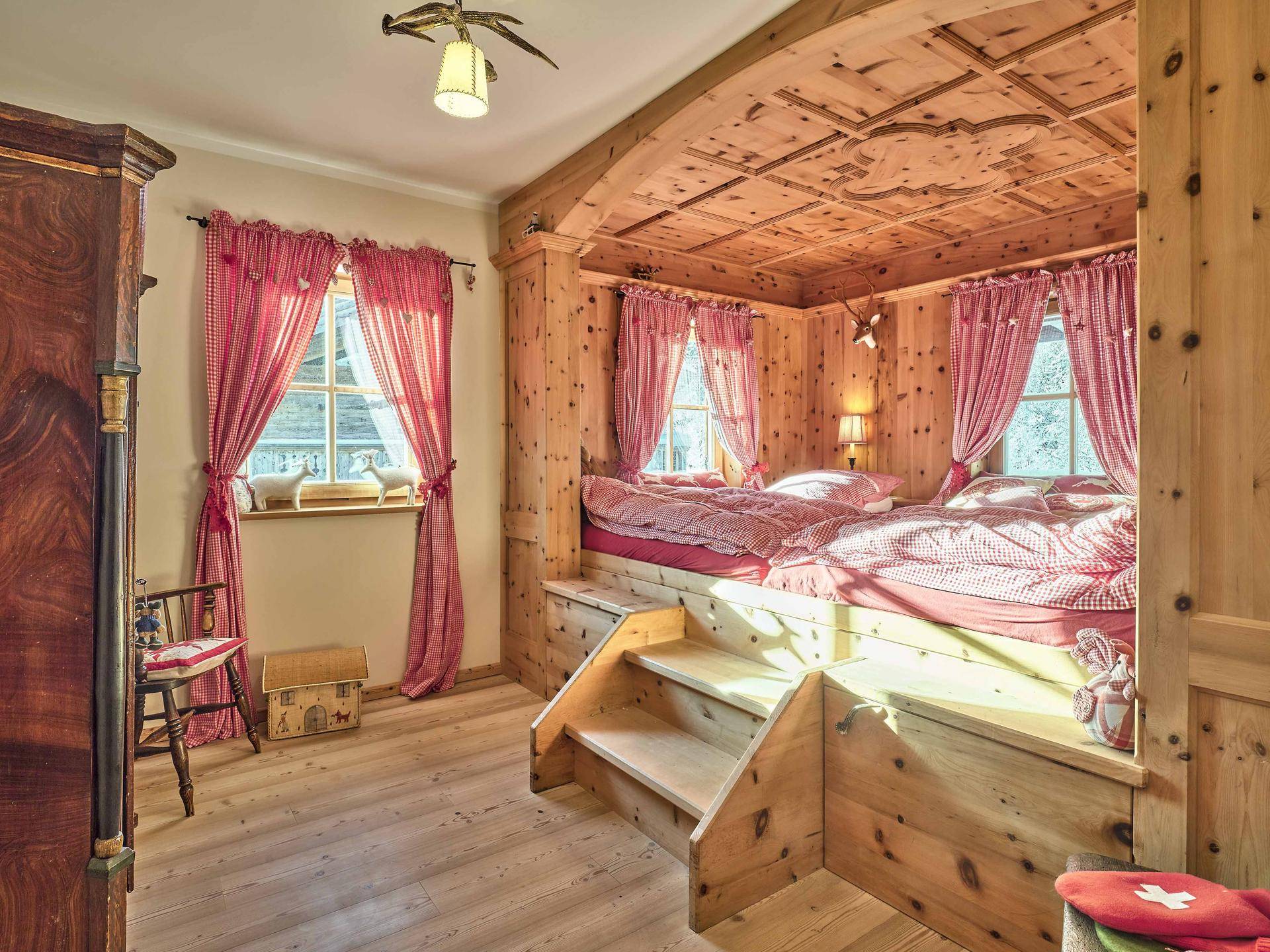 Charmantes Schlafzimmer mit eingebautem Holzdoppelbett, karierten Vorhängen und Holztäfelung.