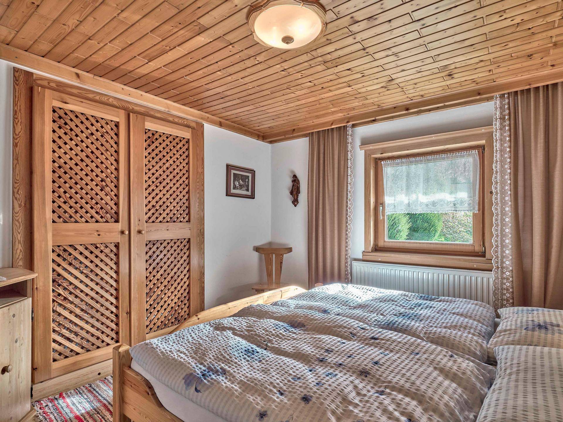 Helles Schlafzimmer mit Holzdecke, Einbauschränken und Doppelbett im Landhausstil.