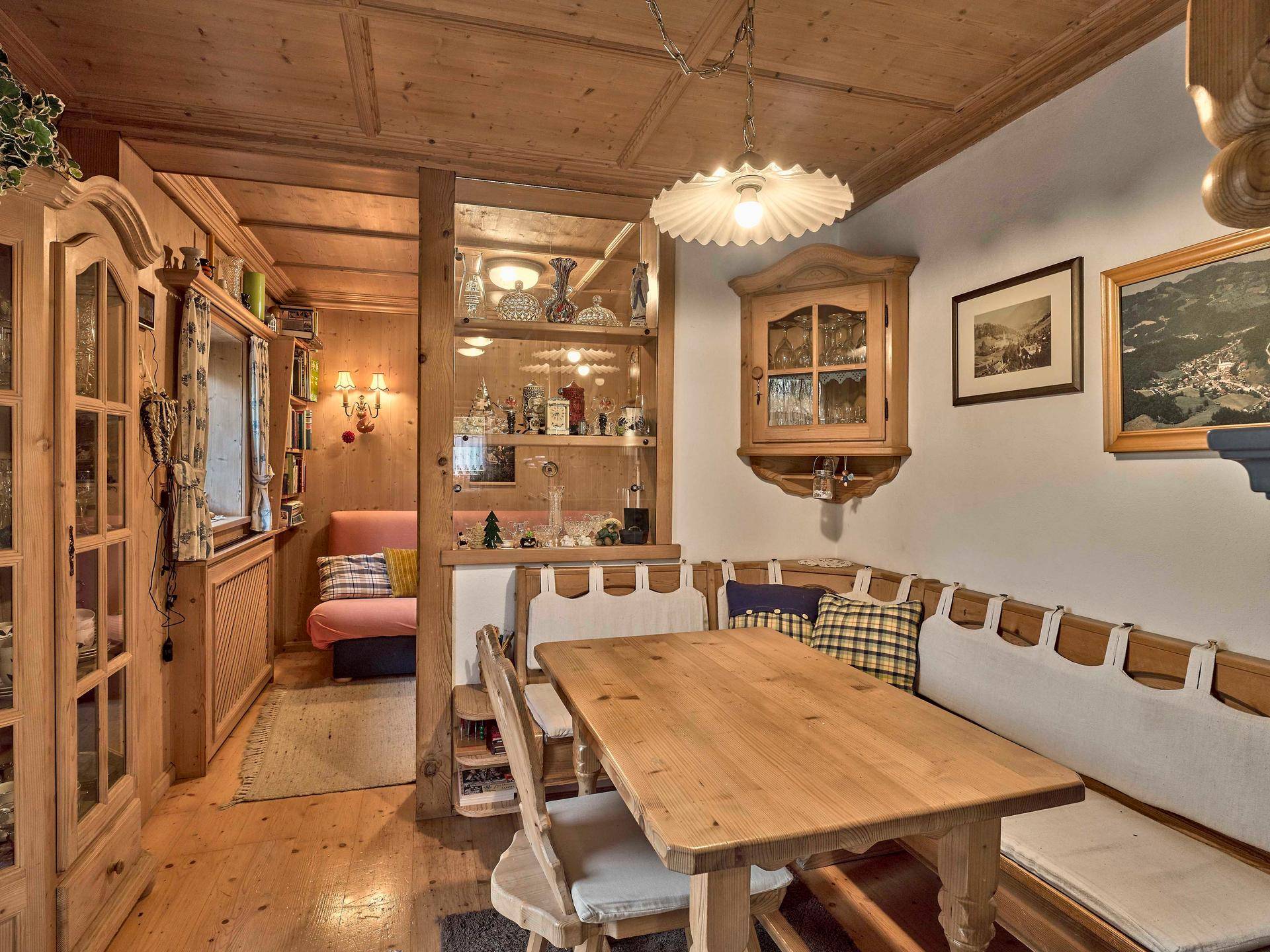 Traditioneller Essbereich mit Holztisch, Eckbank und Blick in den angrenzenden Wohnbereich.