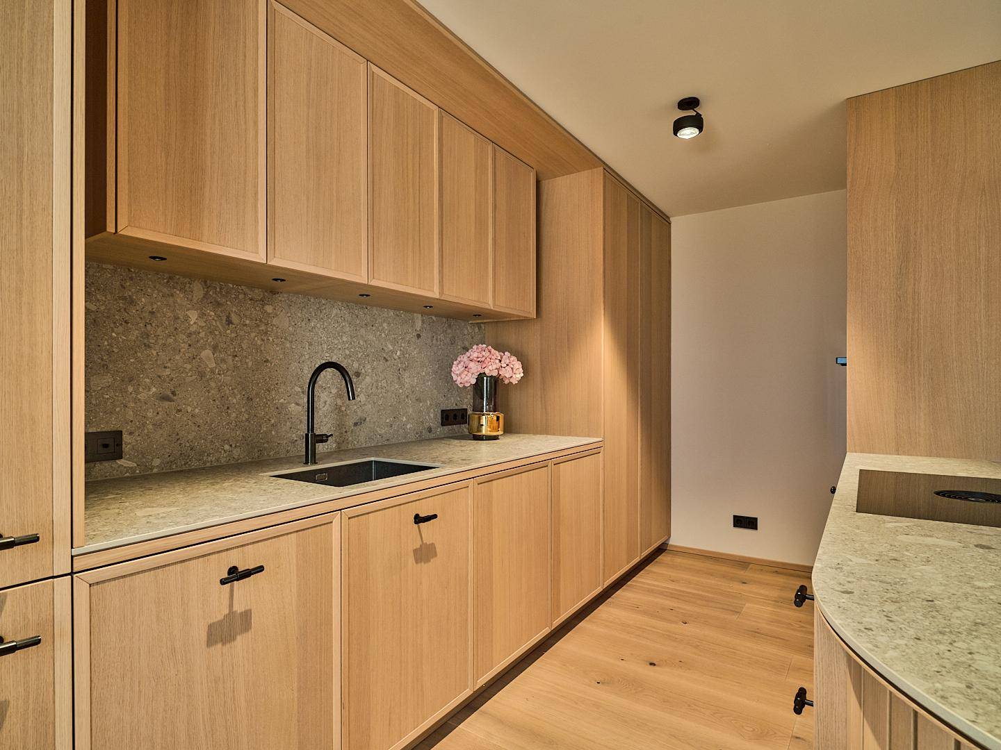 Elegante Holzküche mit Stein-Arbeitsplatte und integrierter Spüle in modernem Design.