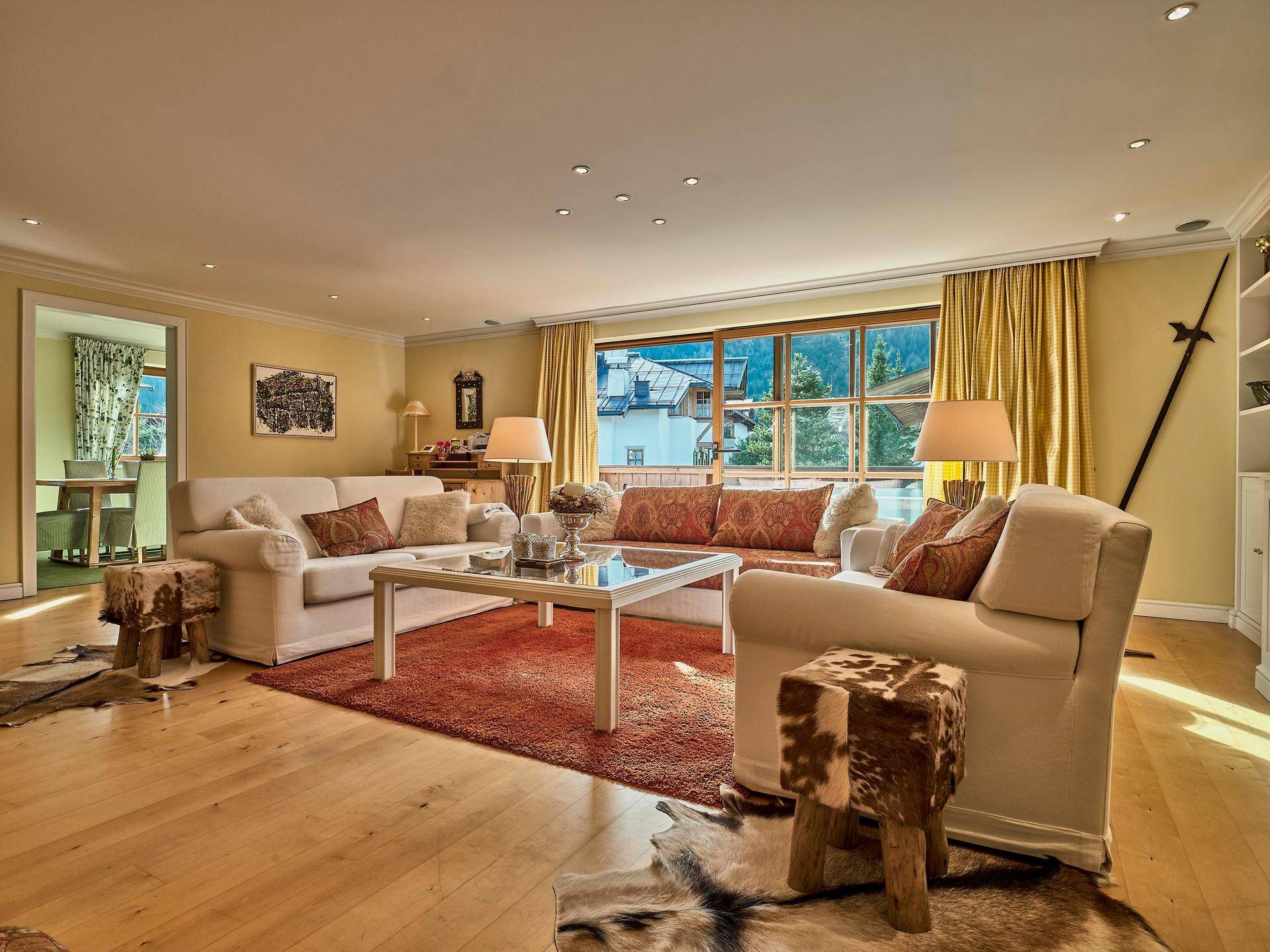 Gemütliches Wohnzimmer mit Holzboden, bequemen Sofas und großem Fenster mit Blick ins Grüne.