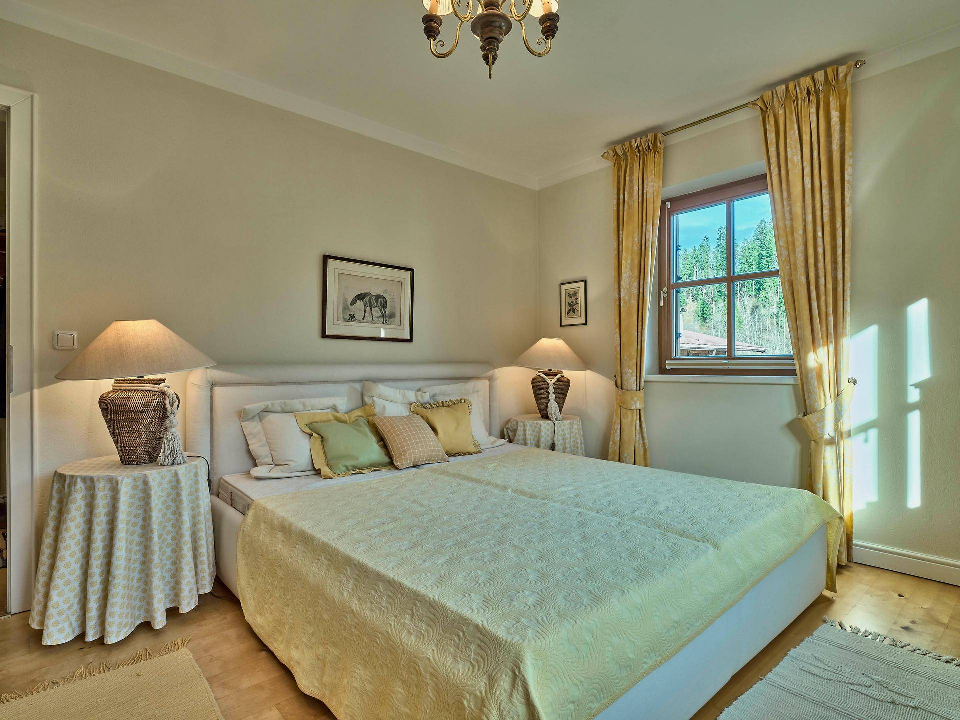 Helles Schlafzimmer mit Doppelbett, Holzboden und gelben Vorhängen am Fenster.
