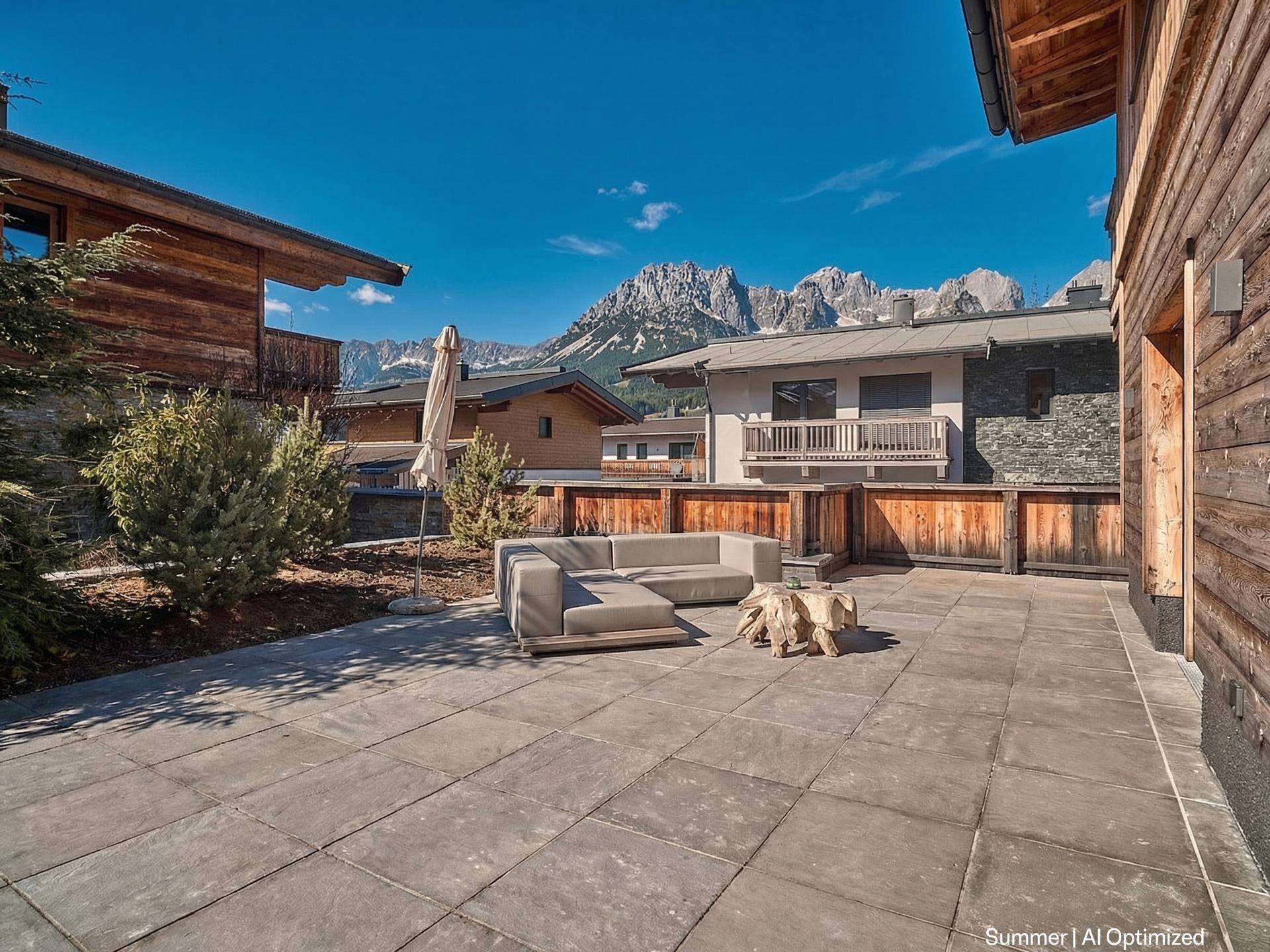 Großzügige gepflasterte Terrasse mit Lounge-Möbeln und weitem Blick auf die Berge.