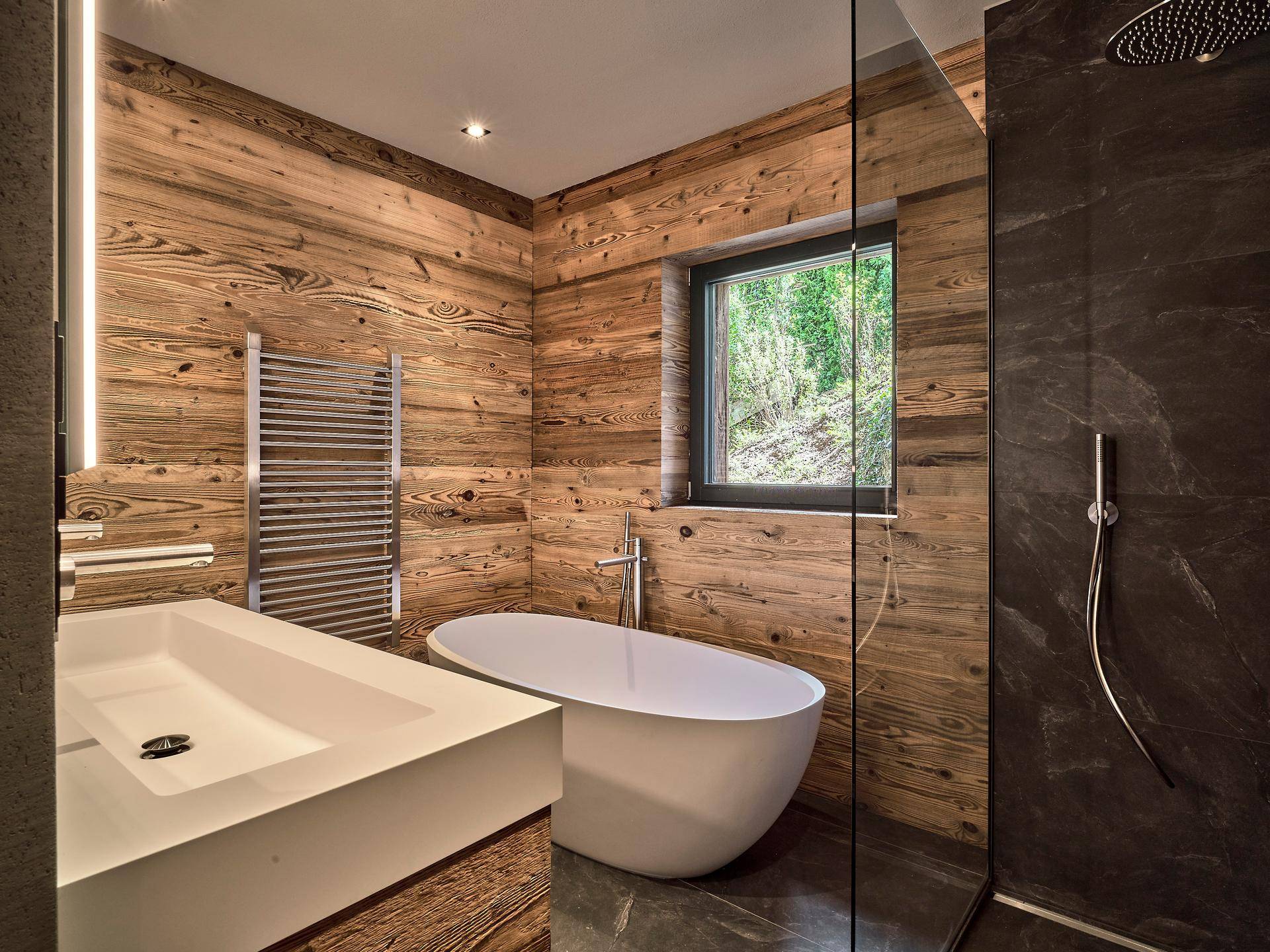 Modernes Badezimmer mit Holzwänden, freistehender Badewanne, begehbarer Dusche und Fenster.