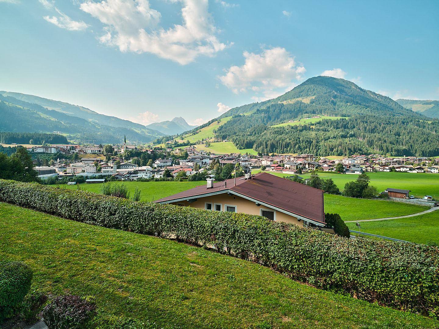 Panoramablick auf ein Haus in einer grünen Berglandschaft mit weitem Horizont.