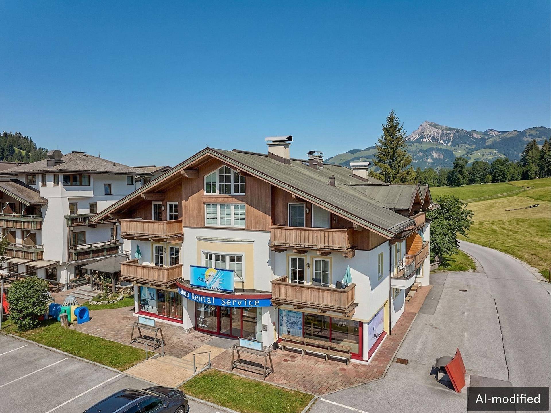 Traditionelles Gebäude im Alpenstil mit Balkonen, Geschäften im Erdgeschoss und Bergblick.